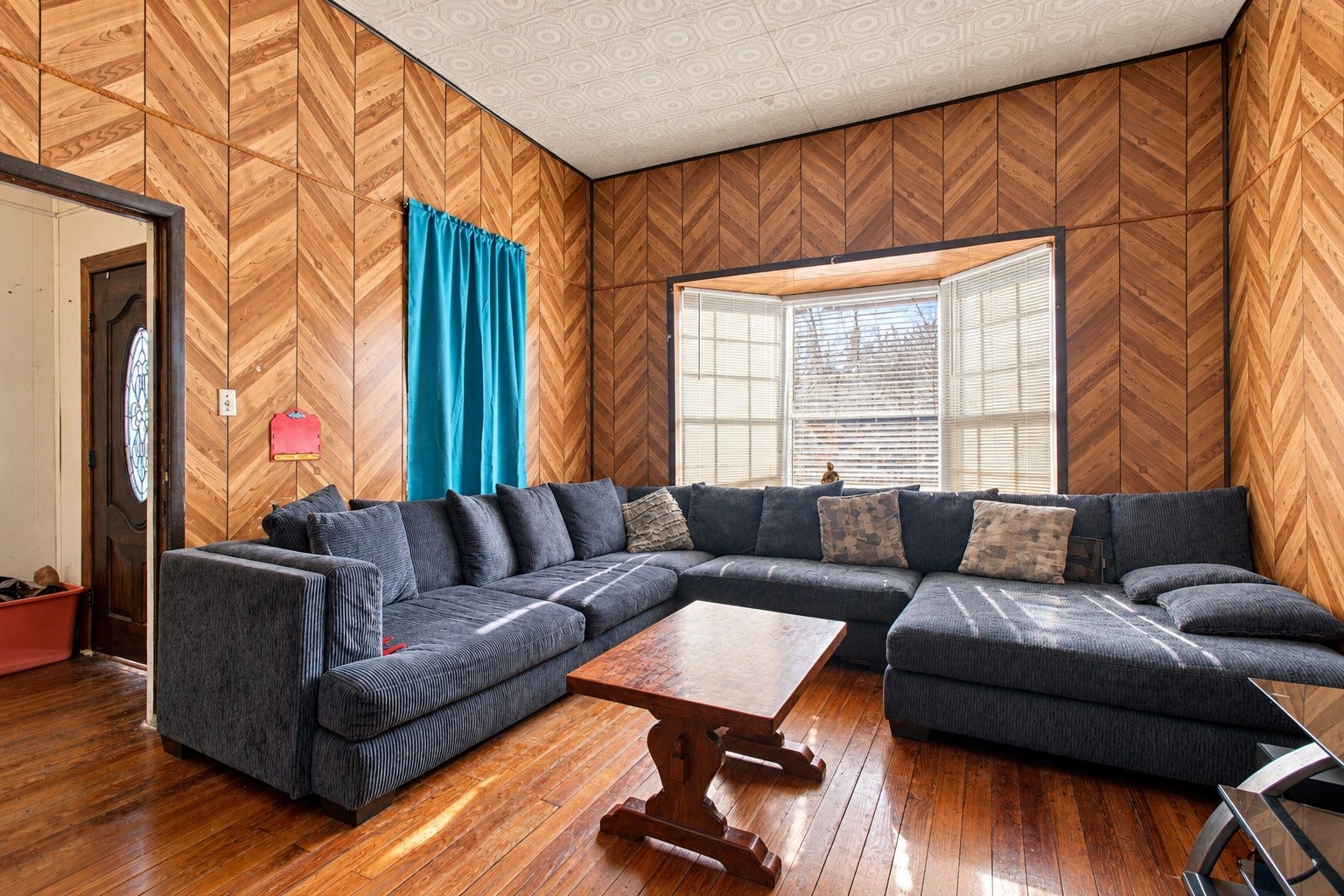 2120 Everett Street, Houston, TX 77009 Front living room featuring distinctive chevron-pattern accent walls, warm tones, coordinating flooring, and natural light.