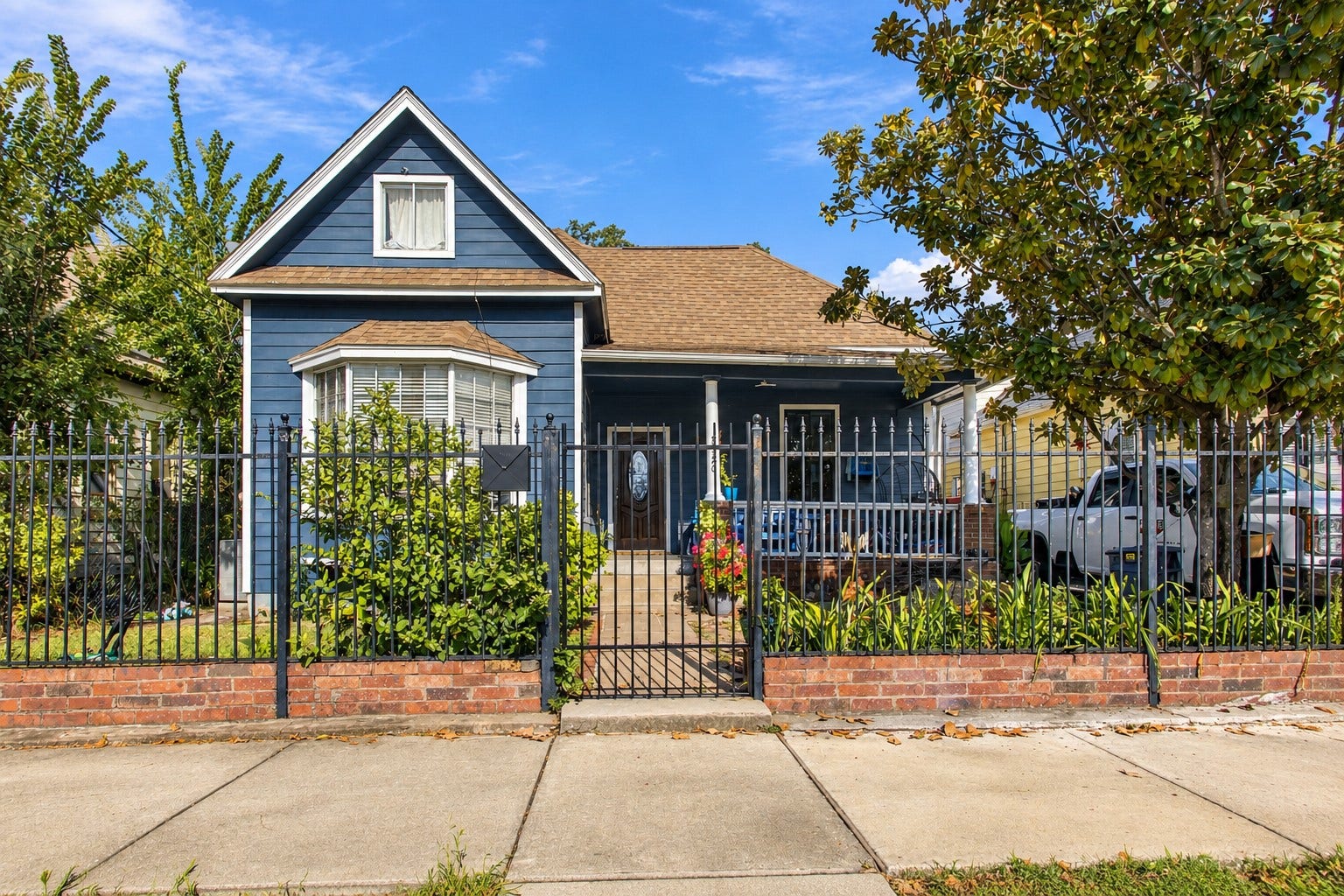 2120 Everett Street, Houston, TX 77009 Front view of the home featuring a covered porch, mature landscaping, and iron fencing.