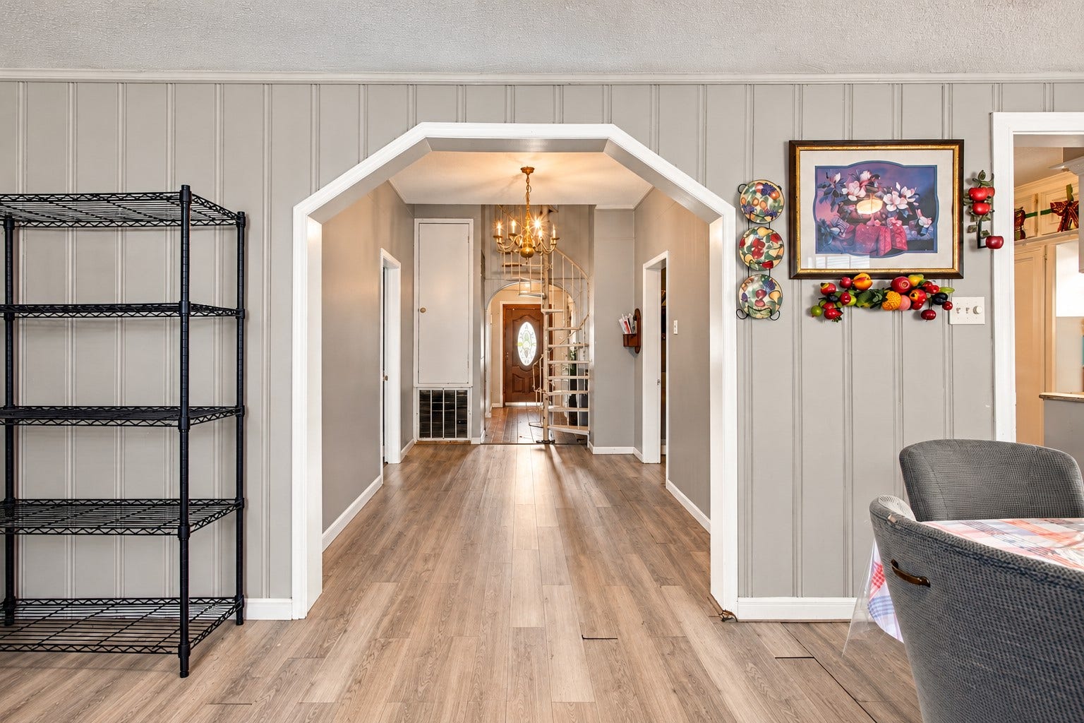 2120 Everett Street, Houston, TX 77009 Open view from the dining area toward the entryway, showcasing the arched opening, spiral staircase, and vinyl flooring.
