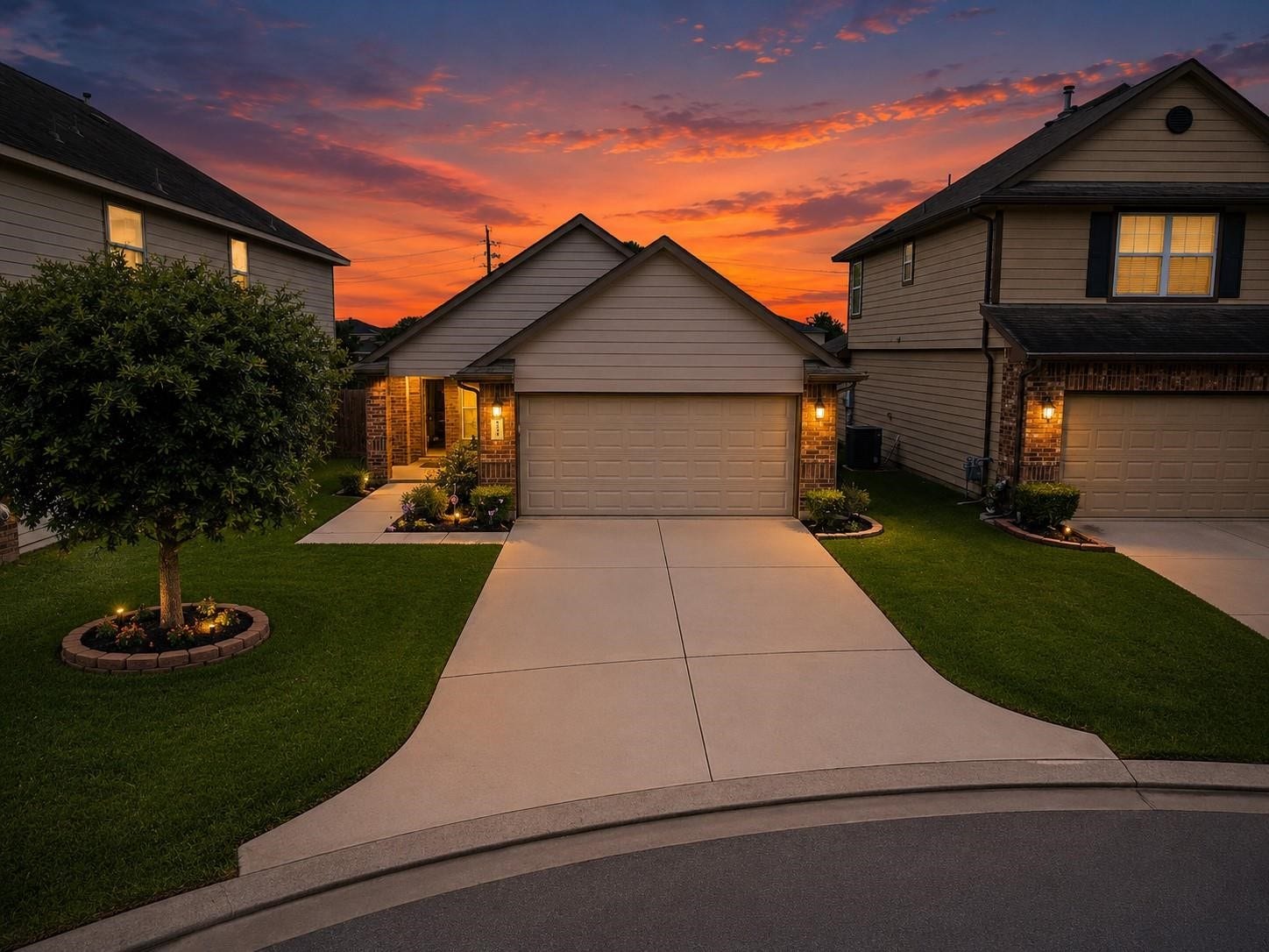 12710 City Green Trail, Houston, TX 77044 This photo showcases a charming suburban home with a well-maintained front lawn and a two-car garage. The property is beautifully lit with warm exterior lights, and the sunset sky adds a picturesque backdrop.