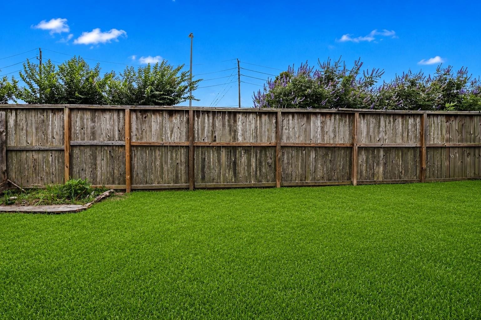 12710 City Green Trail, Houston, TX 77044 This photo showcases a spacious backyard with lush, green grass enclosed by a wooden fence, providing privacy and a serene outdoor space. The area is ideal for gardening, relaxation, or outdoor activities.