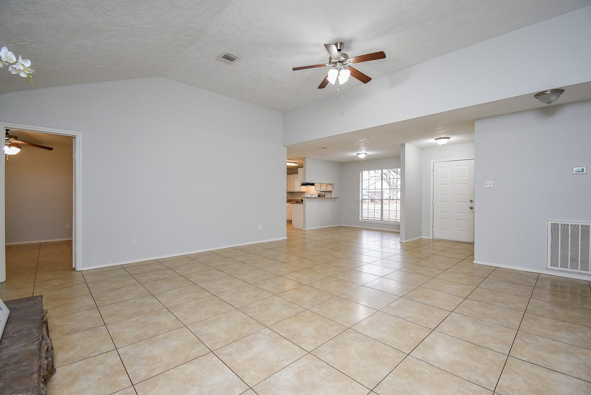 16806 Red Gully Drive, Sugar Land, TX 77498 This spacious living area features neutral tile flooring, high ceilings with ceiling fans, and an open layout that flows into the kitchen. The room is bright with natural light, offering a welcoming entryway and access to adjoining rooms.