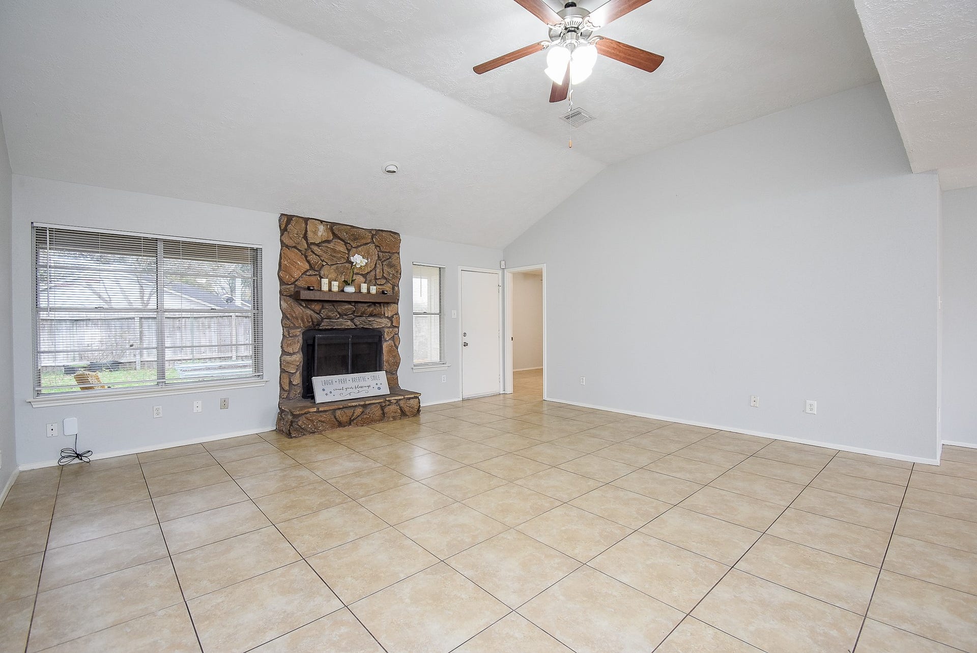 16806 Red Gully Drive, Sugar Land, TX 77498 Spacious living room with high ceilings, featuring a stone fireplace and large windows. The room has tile flooring and neutral walls, creating a bright and airy feel.