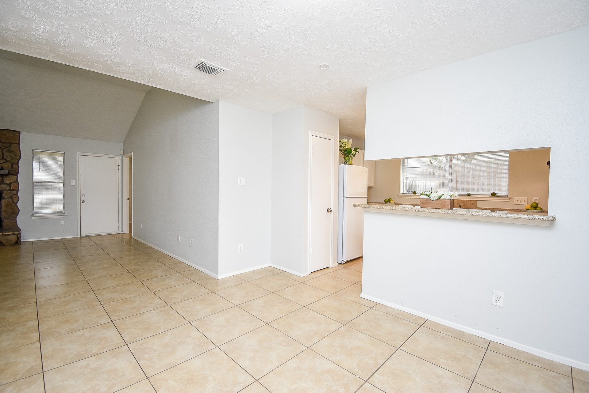 16806 Red Gully Drive, Sugar Land, TX 77498 This bright, open-concept space features tile flooring, a partial view of the kitchen with a breakfast bar, and access to outdoor light through a window near the entrance.