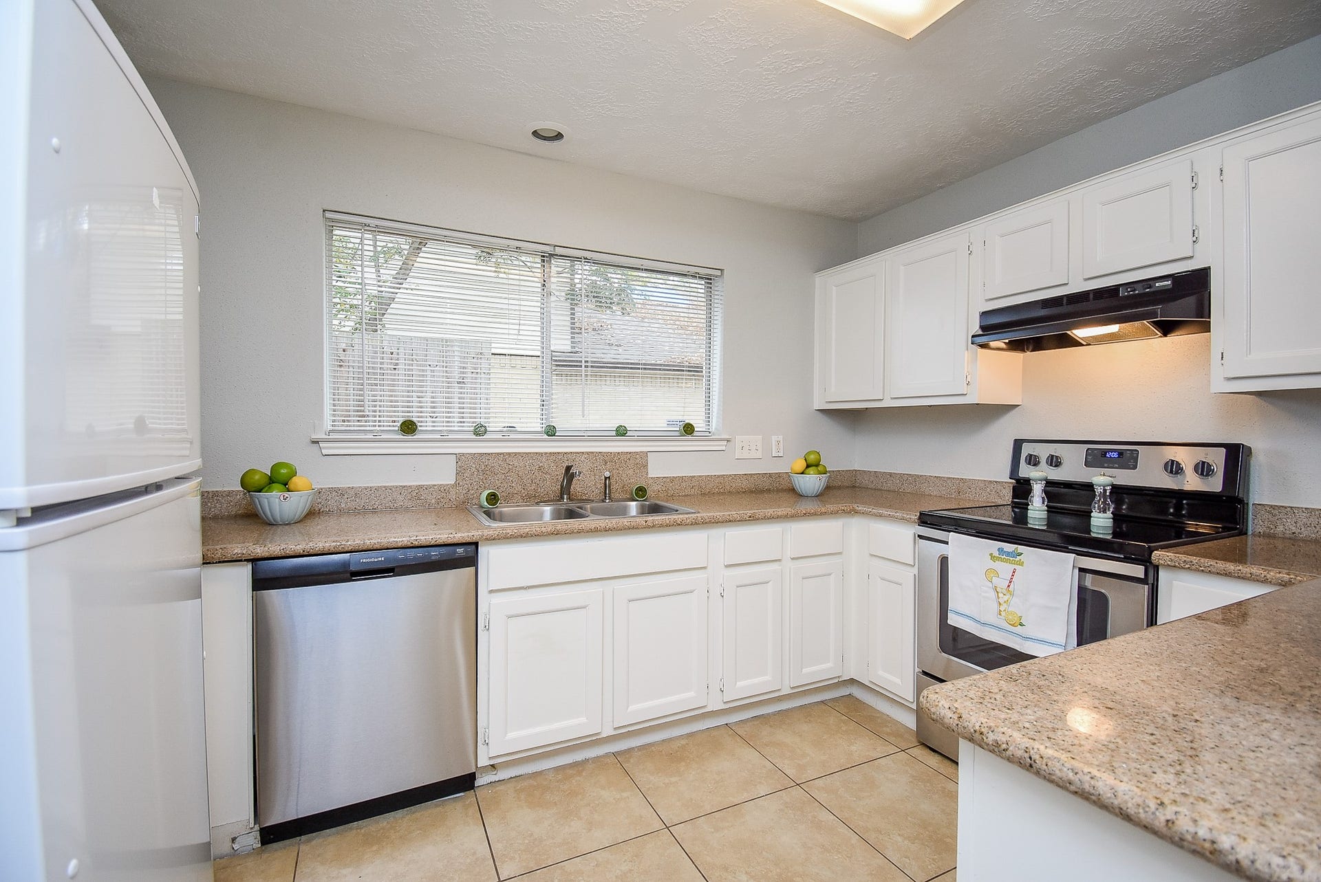 16806 Red Gully Drive, Sugar Land, TX 77498 Bright, modern kitchen with white cabinetry, stainless steel appliances, and granite countertops. The space features a large window for natural light and tiled flooring for easy maintenance.