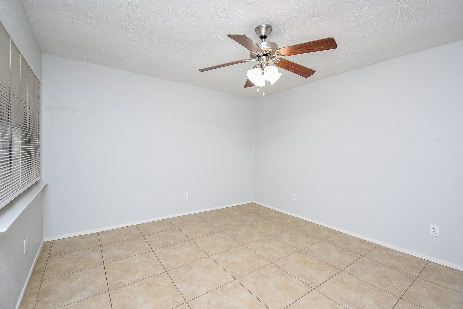 16806 Red Gully Drive, Sugar Land, TX 77498 This room features neutral tile flooring, light gray walls, a ceiling fan with lights, and a window with blinds, offering a bright and airy atmosphere.