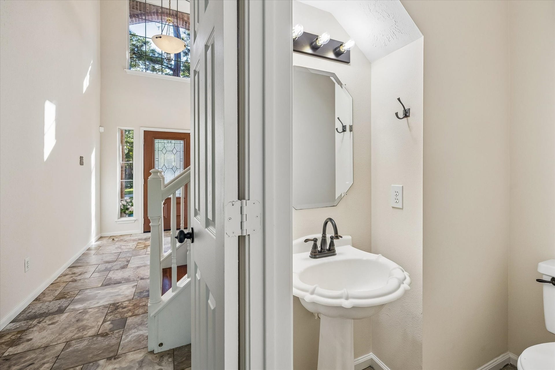 11 Merryvale Drive, The Woodlands, TX 77382 The powder bath is conveniently located just off the entry, offering easy access for guests with a charming pedestal sink and decorative mirror.