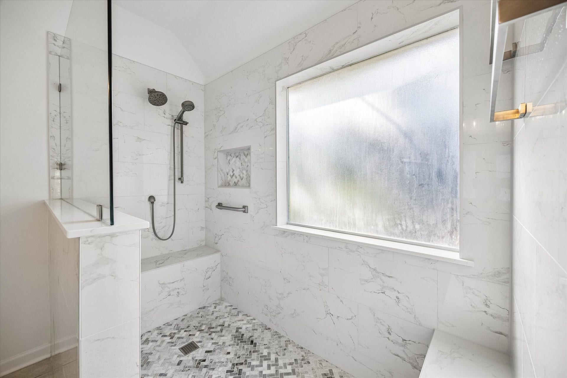 11 Merryvale Drive, The Woodlands, TX 77382 The oversized walk-in shower features decorative mosaic floor, built-in shelving, towel bars, bench, and a sleek glass enclosure!