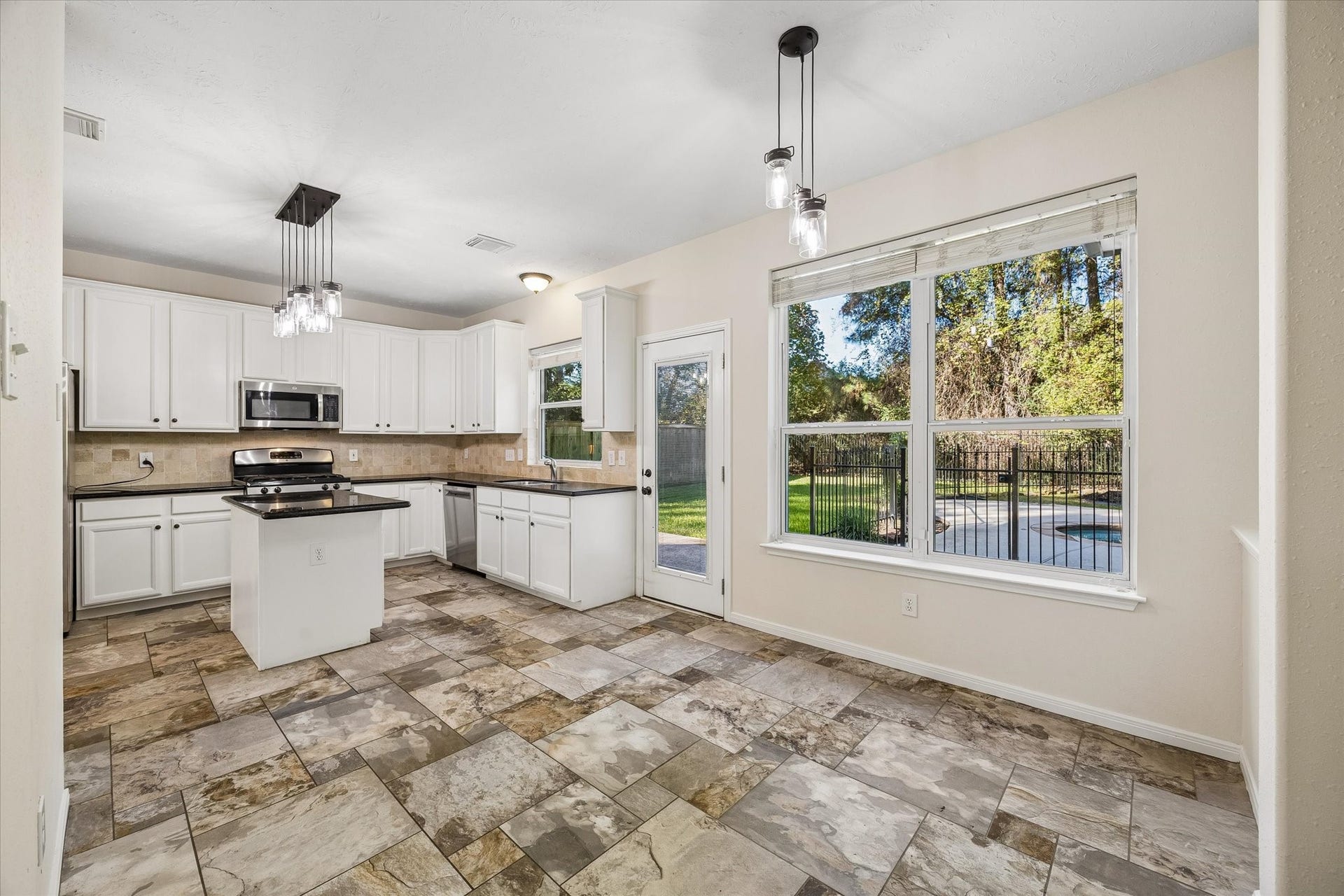 11 Merryvale Drive, The Woodlands, TX 77382 The kitchen flows seamlessly into the breakfast area, where large windows fill the space with natural light and offer lovely views of the sparkling pool and backyard.