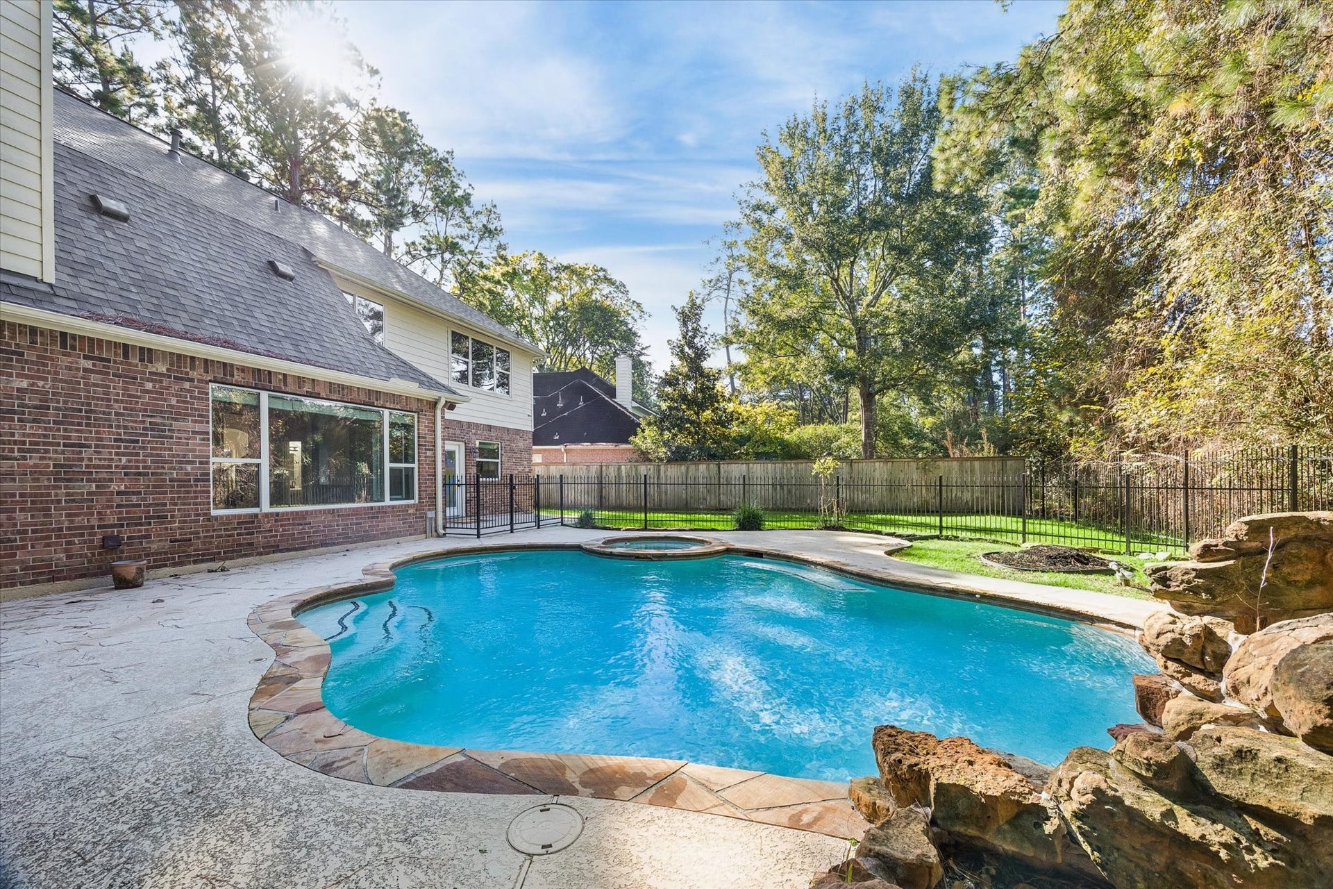11 Merryvale Drive, The Woodlands, TX 77382 Another view of the beautiful pool and spa, surrounded by a spacious patio and mature trees! The pool has been resurfaced with a pebble tec finish and features a heater and child safe fence.