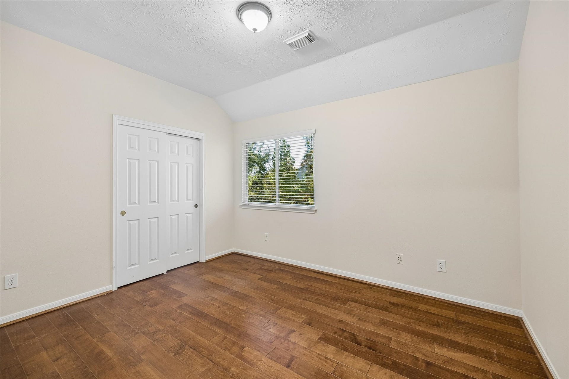 11 Merryvale Drive, The Woodlands, TX 77382 The secondary bedroom features warm wood flooring, adding a rich touch of character while complementing the neutral walls and filling the space with a bright, inviting feel.