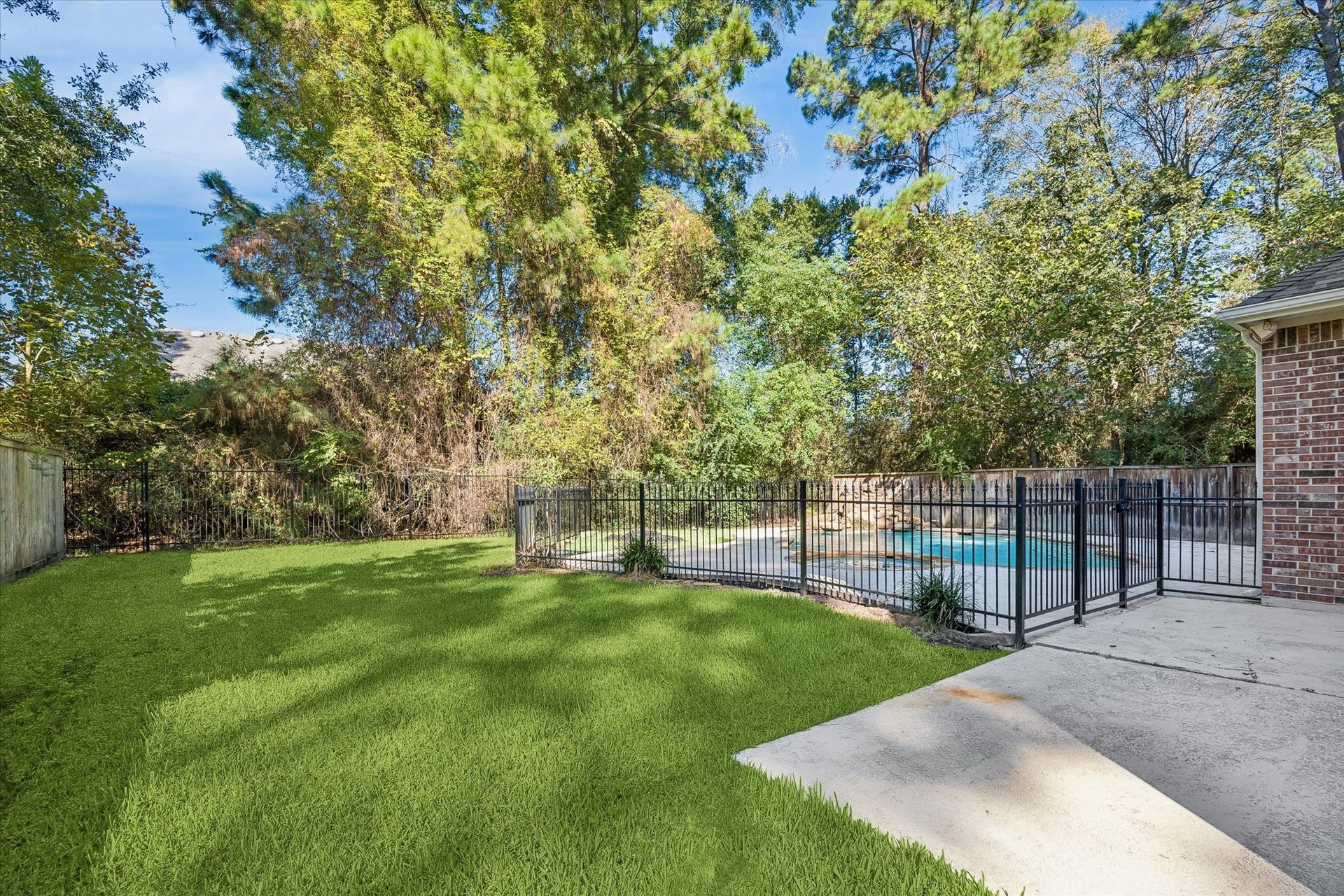 11 Merryvale Drive, The Woodlands, TX 77382 The backyard offers additional green space beyond the pool area, providing plenty of room for outdoor activities, gardening, or simply enjoying the spacious yard.