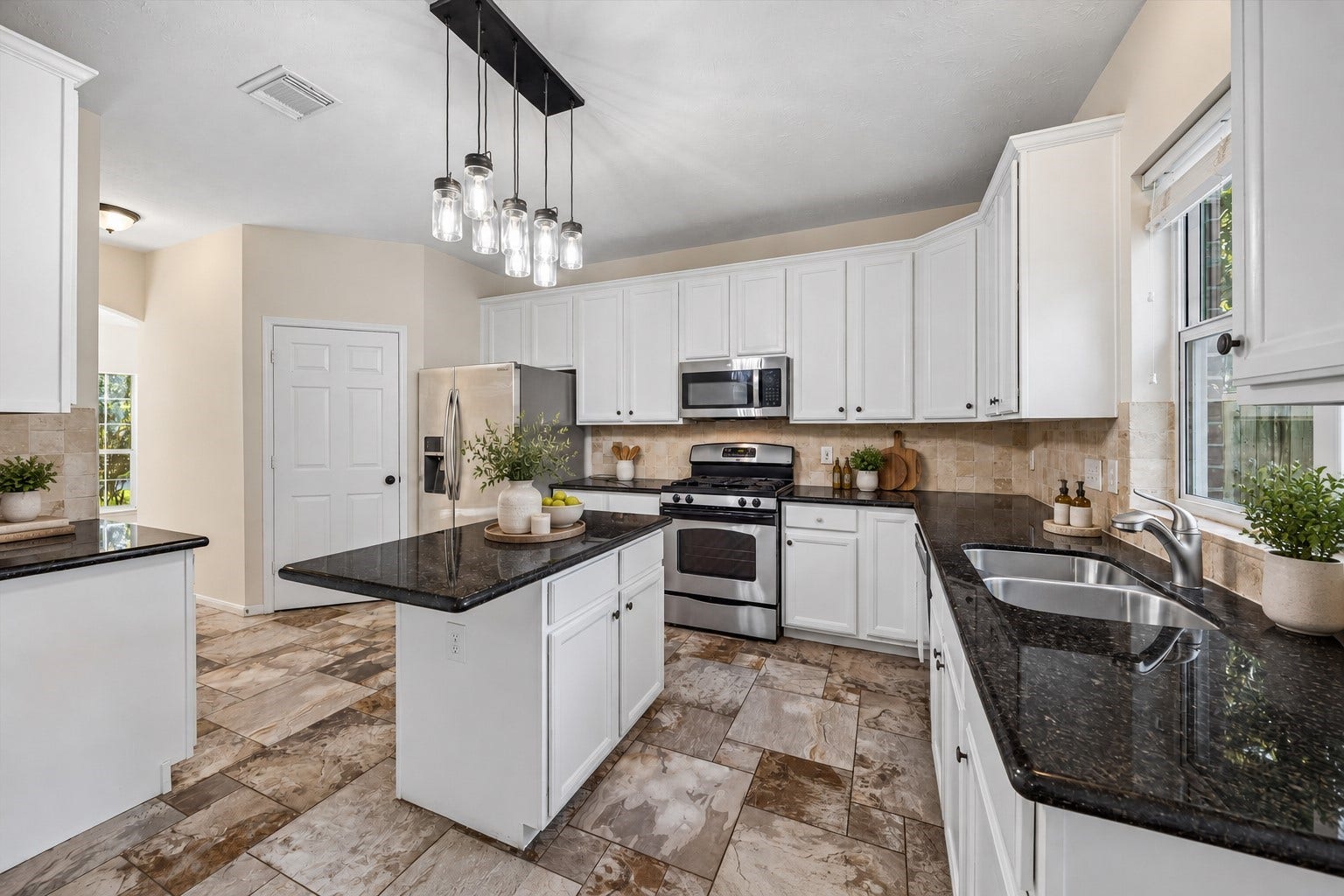 11 Merryvale Drive, The Woodlands, TX 77382 The kitchen features crisp white cabinetry, sleek black granite countertops, and stainless steel appliances. A center island provides additional prep space! Virtually staged with accessories.