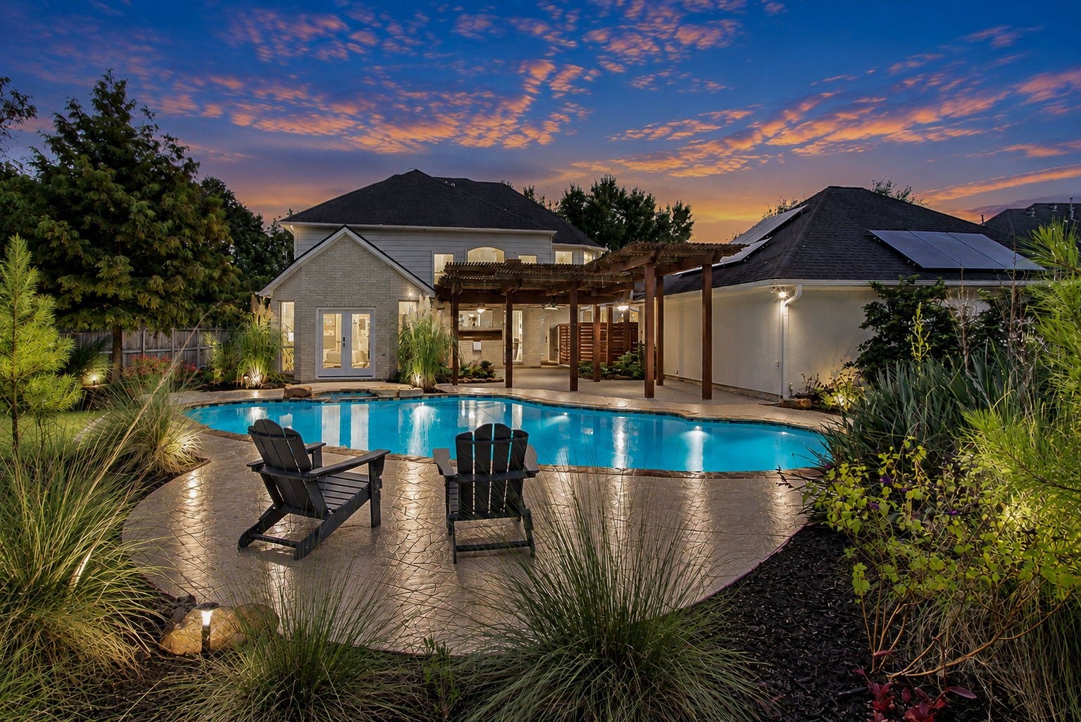 22510 Country Cove Lane, Katy, TX 77494 Experience serene evenings in this elegant backyard featuring a sparkling pool, and lush landscaping under a picturesque sunset sky.