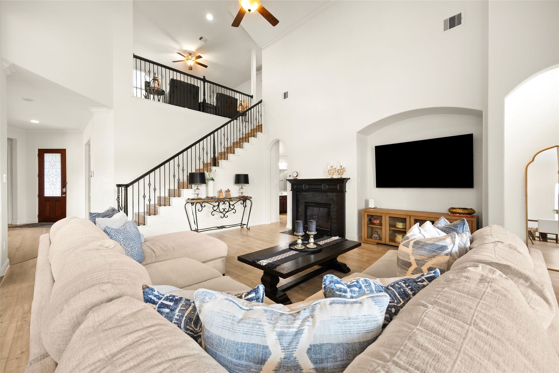 9612 Eden Ridge Lane, Pearland, TX 77584 LIVING ROOM - Light-filled living room with soaring ceilings, a fireplace, and an open staircase overlooking the second-floor family room.
