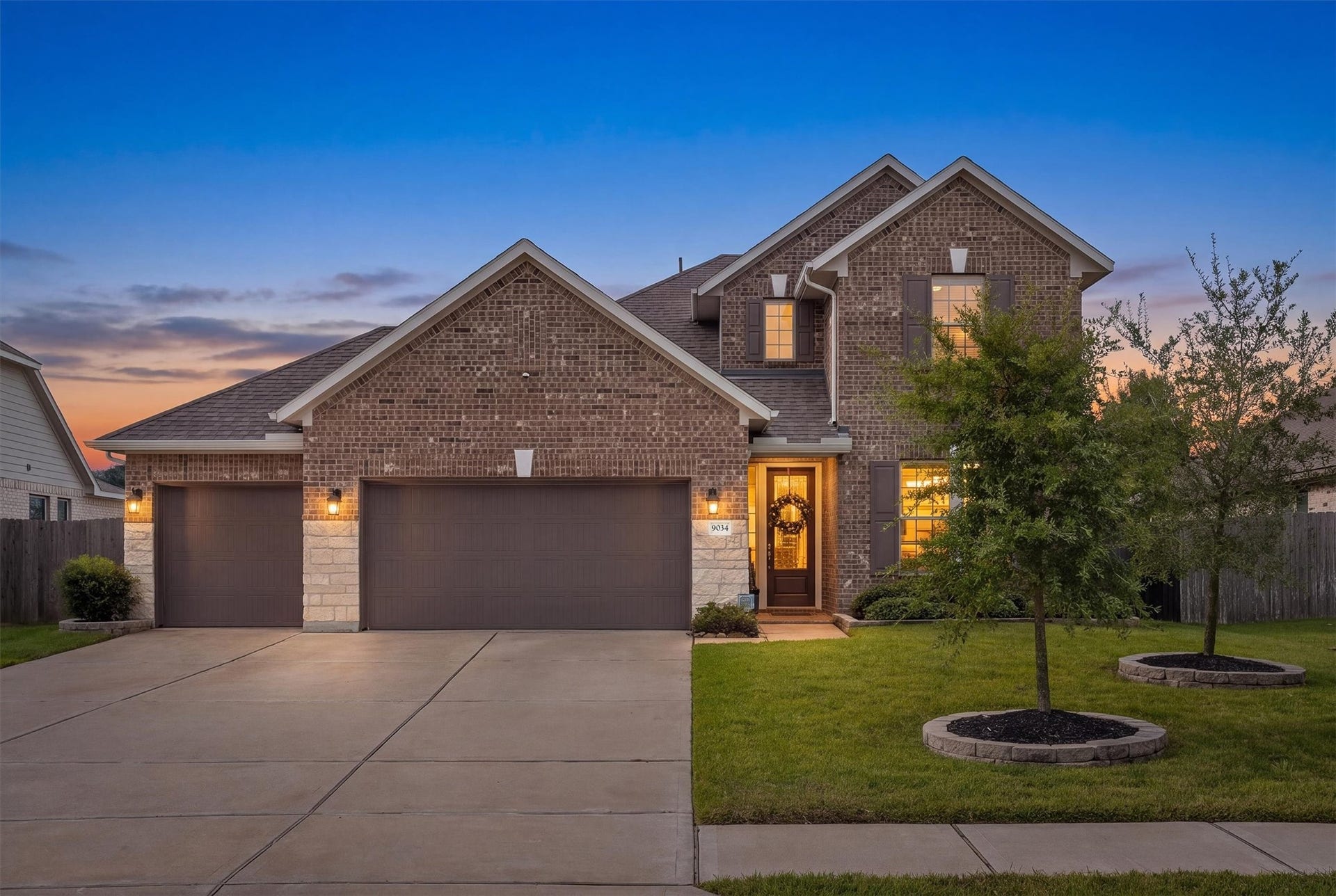 9034 Japonica Drive, Rosenberg, TX 77469 A striking brick and stone facade glowing under a magnificent sunset sky.