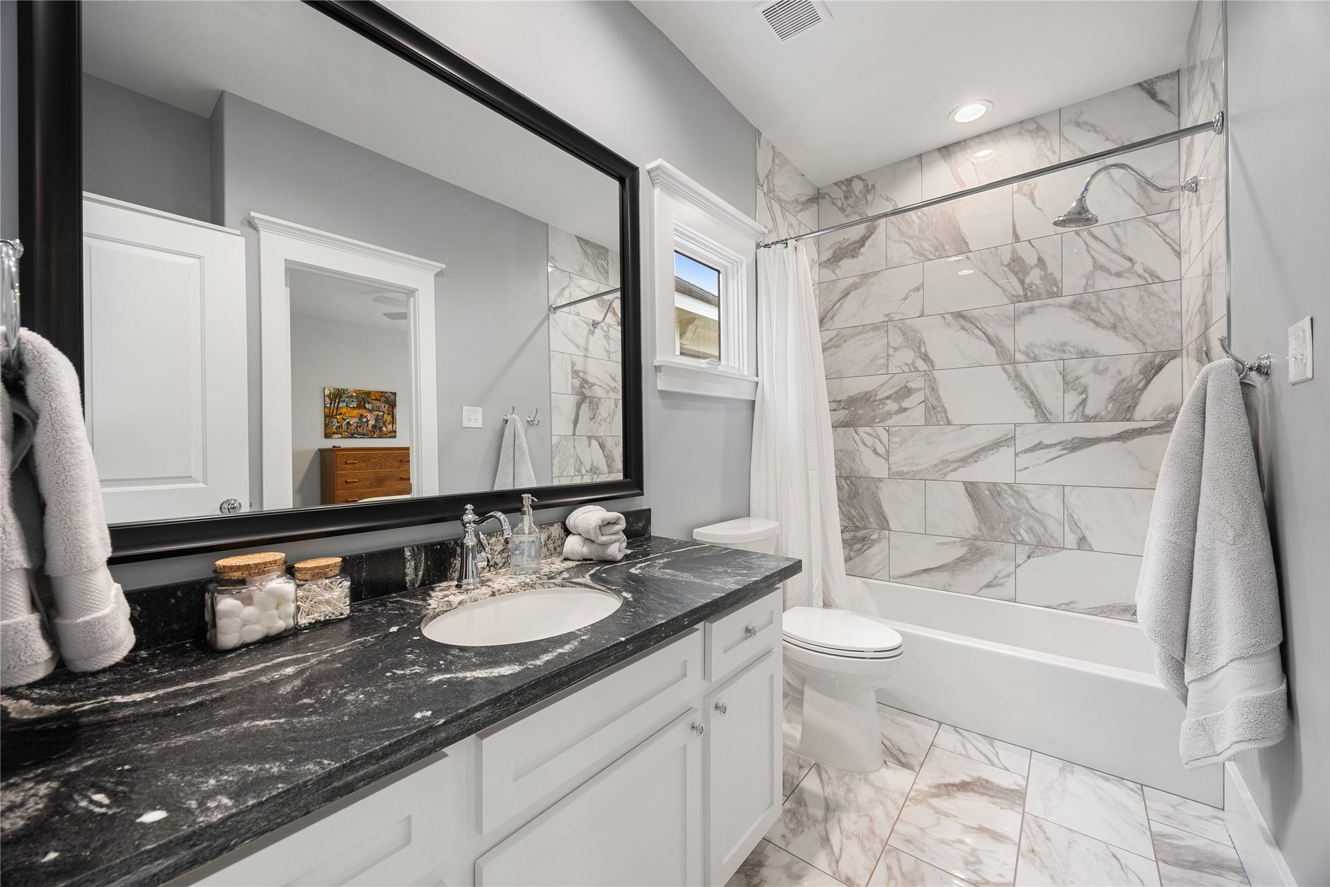 Remodeled secondary bathroom features updated tile, vanity finishes & a tub/shower combination.