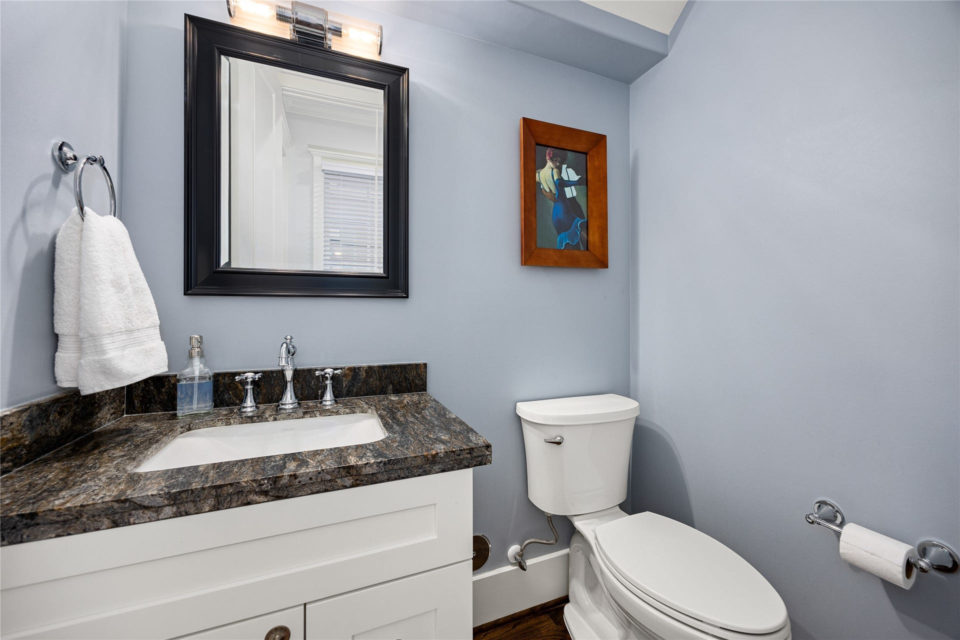 First-floor powder room features an updated vanity with storage, decorative mirror, updated lighting & stylish finishes.