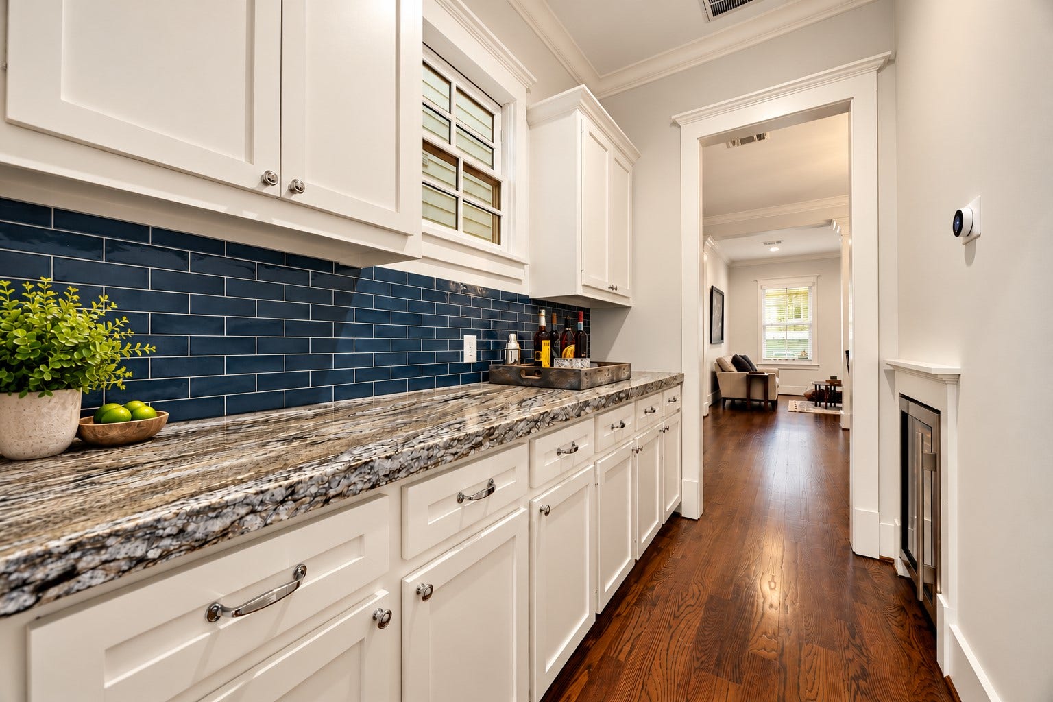 Butlers pantry features extensive cabinetry, leathered Blue Dune granite countertops, striking navy subway tile backsplash & a Sub-Zero wine coolerideal for entertaining & additional storage.
