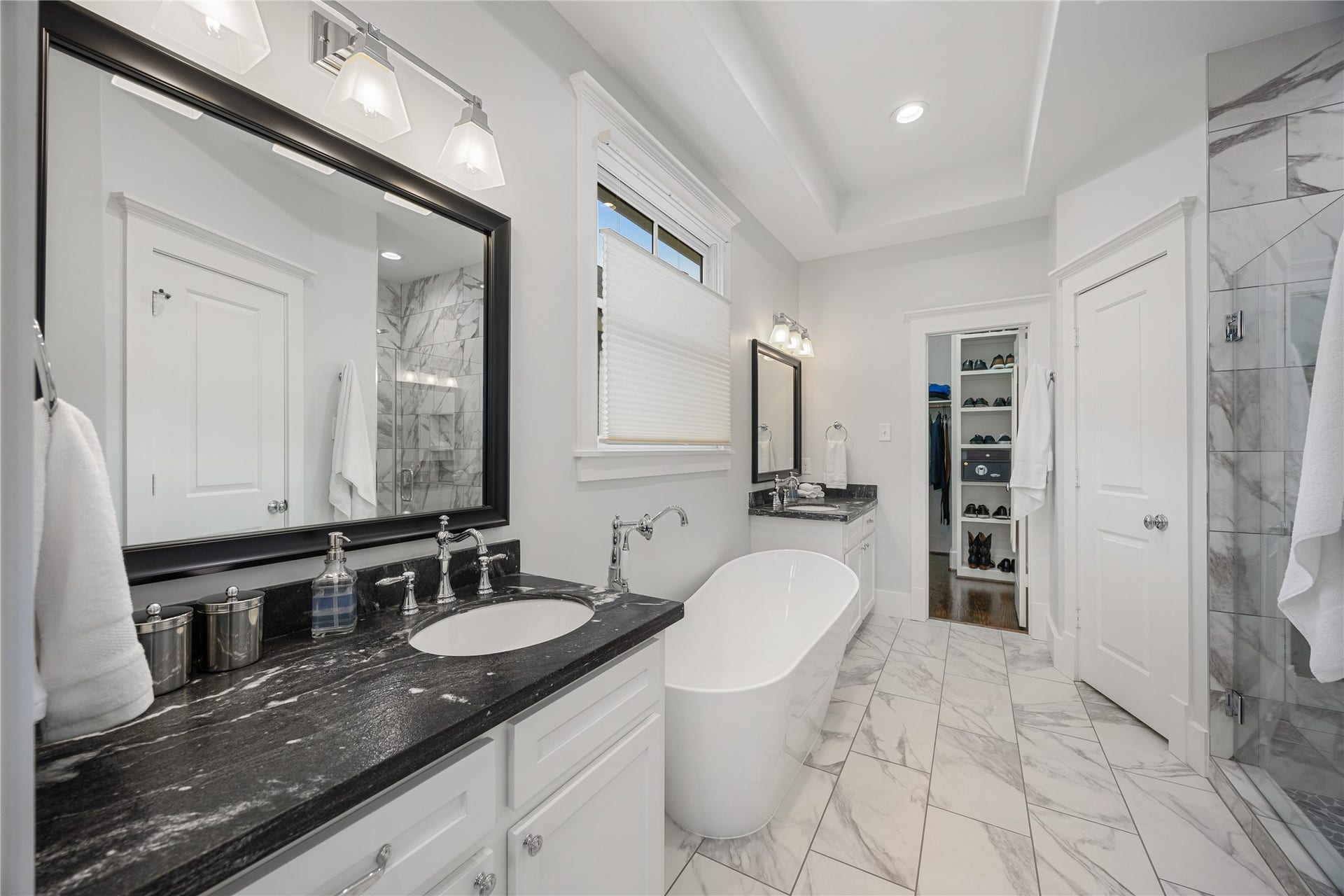 Remodeled primary bathroom features dual sinks, updated soaking tub and tile throughout, and elegant timeless finishes.