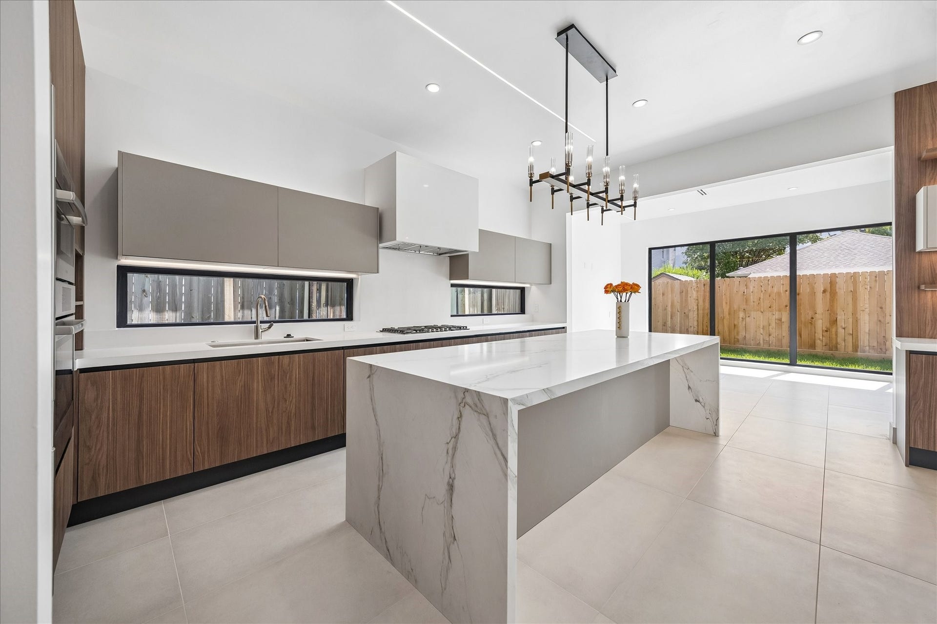 Chefs kitchen with Bosch appliances, a paneled Dacor refrigerator, quartzite island, gas cooktop, double-ovens and beverage center.