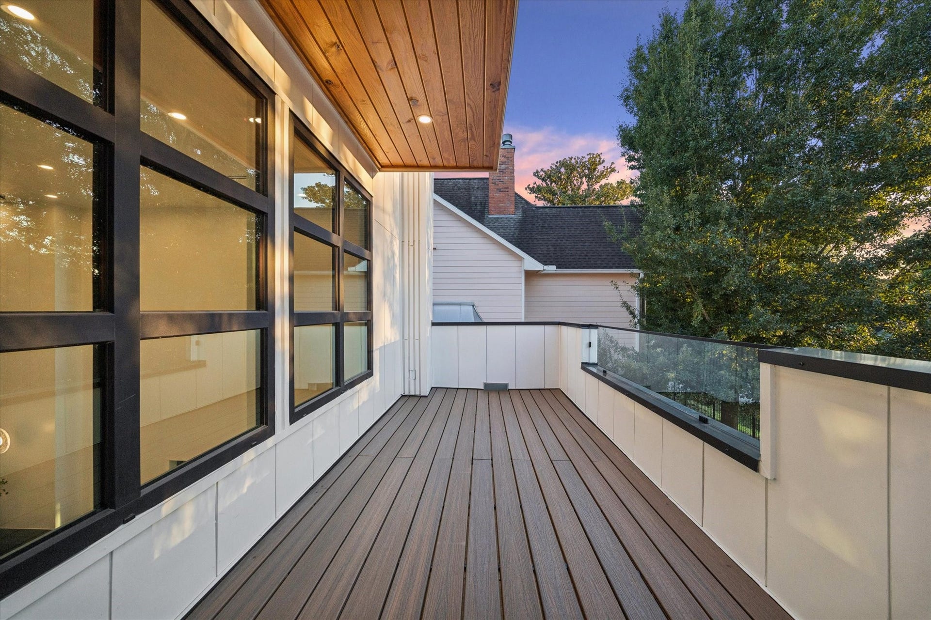 Stylish upper deck with modern glass railing and wood accents, offering a peaceful outdoor retreat with scenic views.