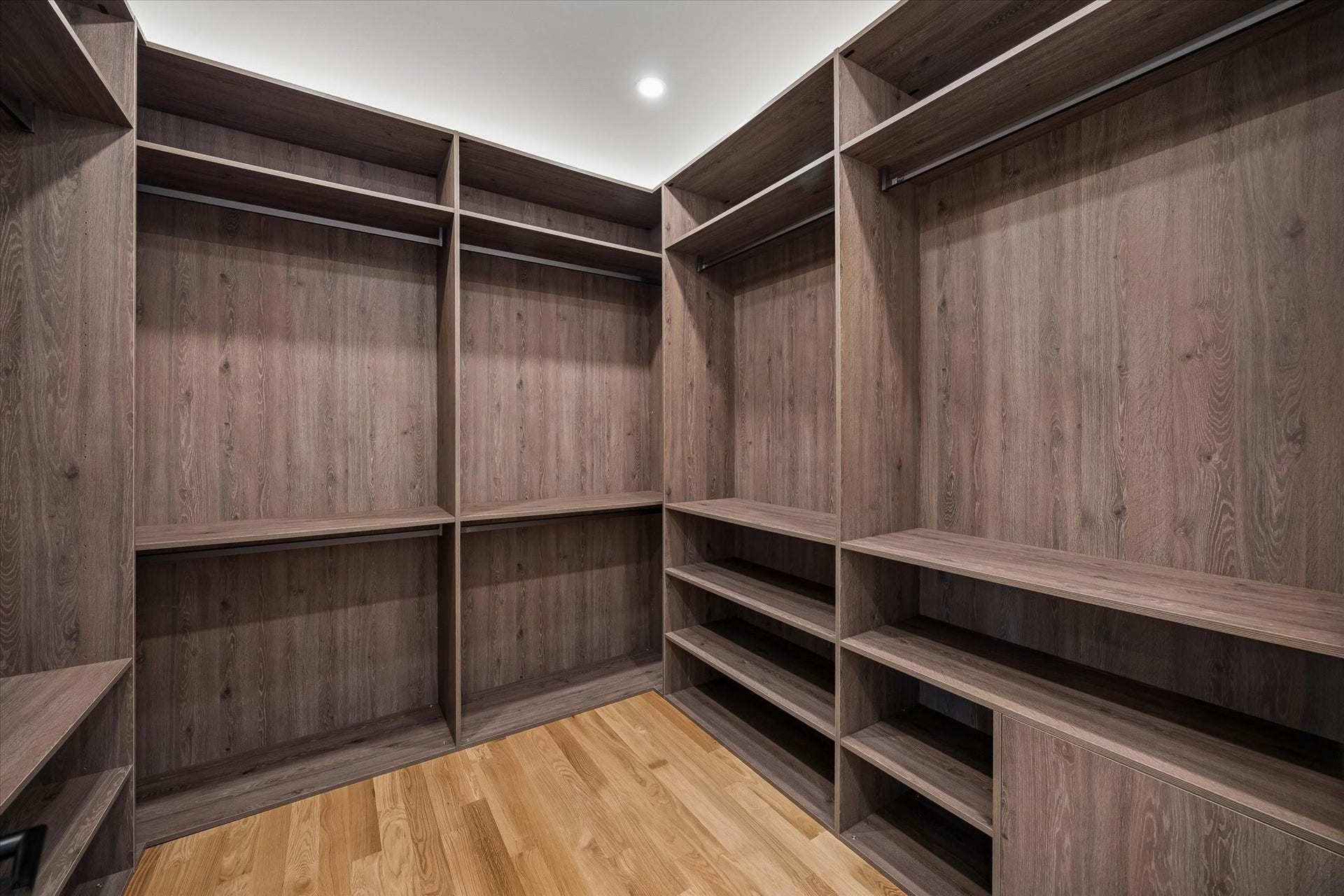 Spacious walk-in closet with custom wood shelving and ample hanging space, perfect for organizing your wardrobe.