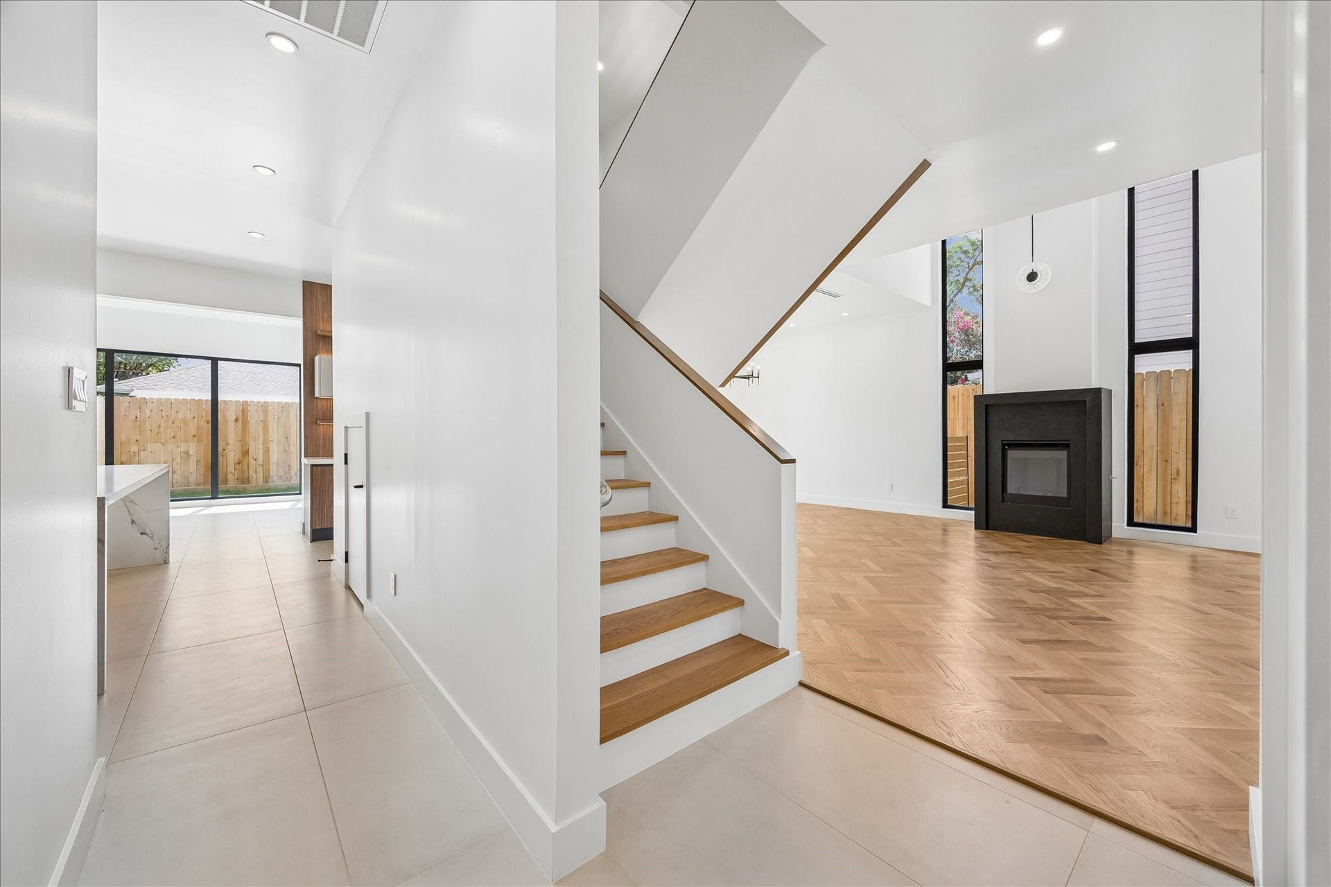 Modern interior featuring an elegant staircase, open living area with a sleek fireplace, and large windows for natural light.