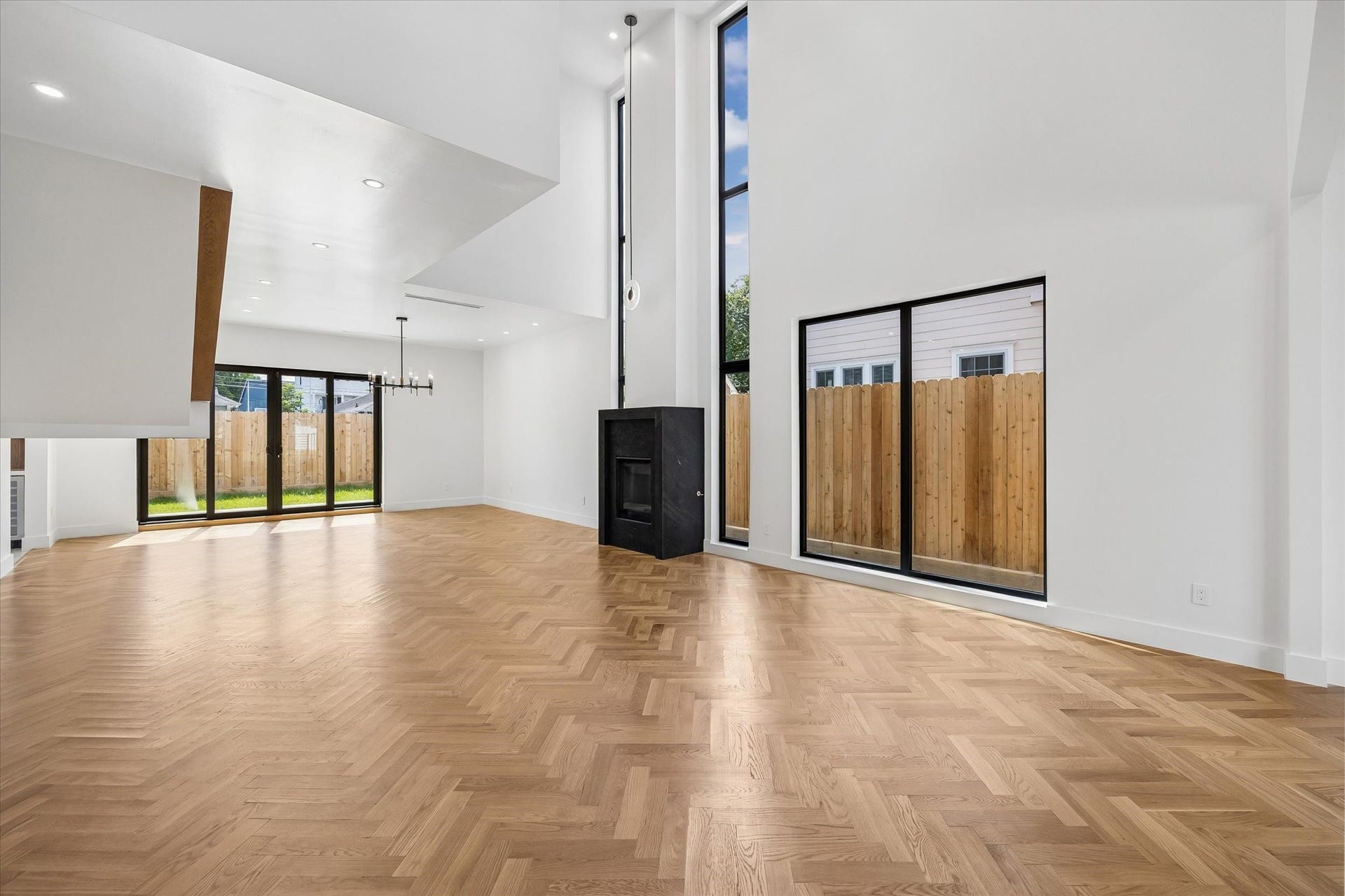 Elegant open-concept dining area featuring a modern chandelier, stylish artwork, and warm wood flooring, seamlessly flowing into a cozy living space with abundant natural light.