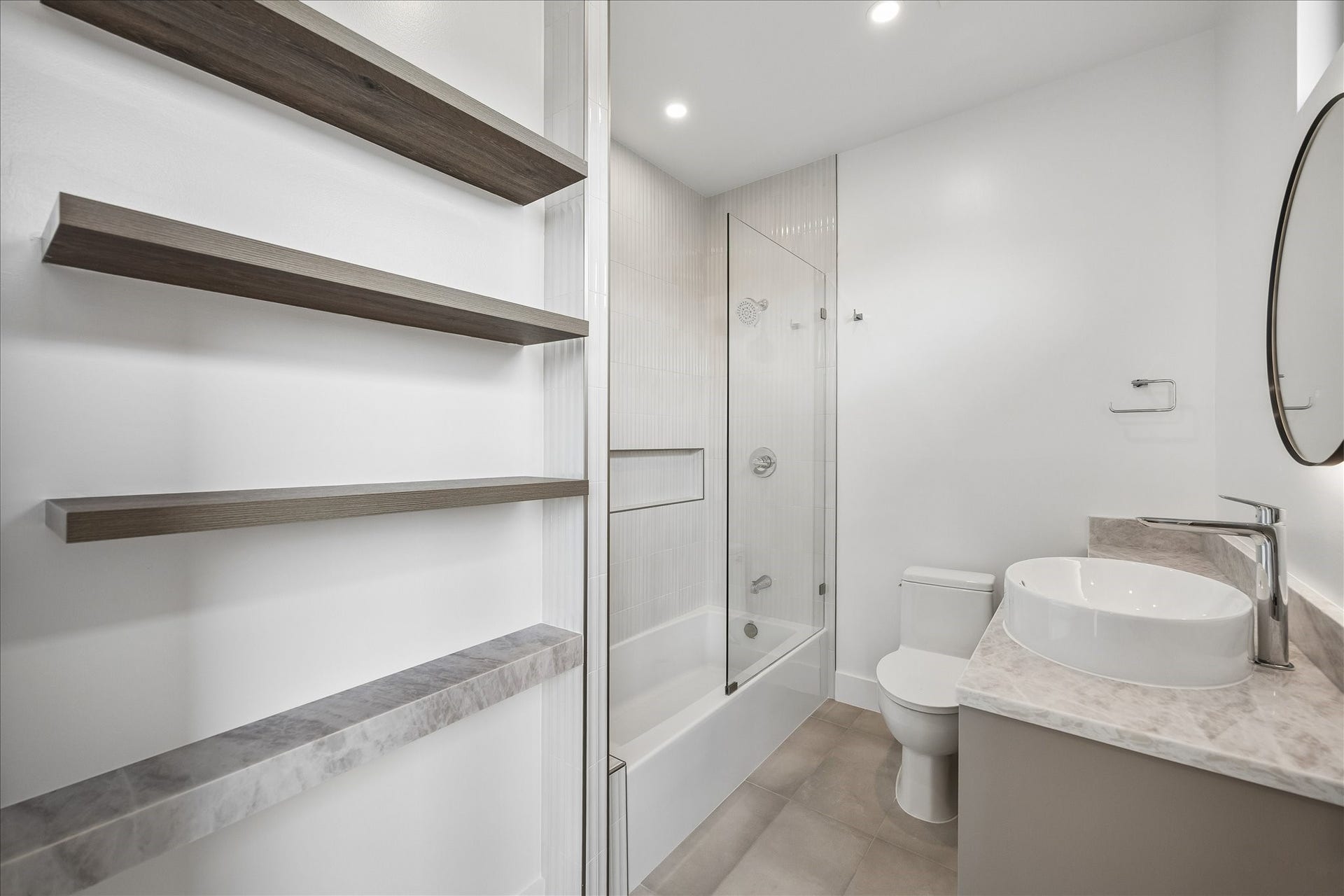 Modern bathroom featuring a glass-enclosed shower-tub combo, elegant vessel sink, and stylish open shelving for a contemporary touch.