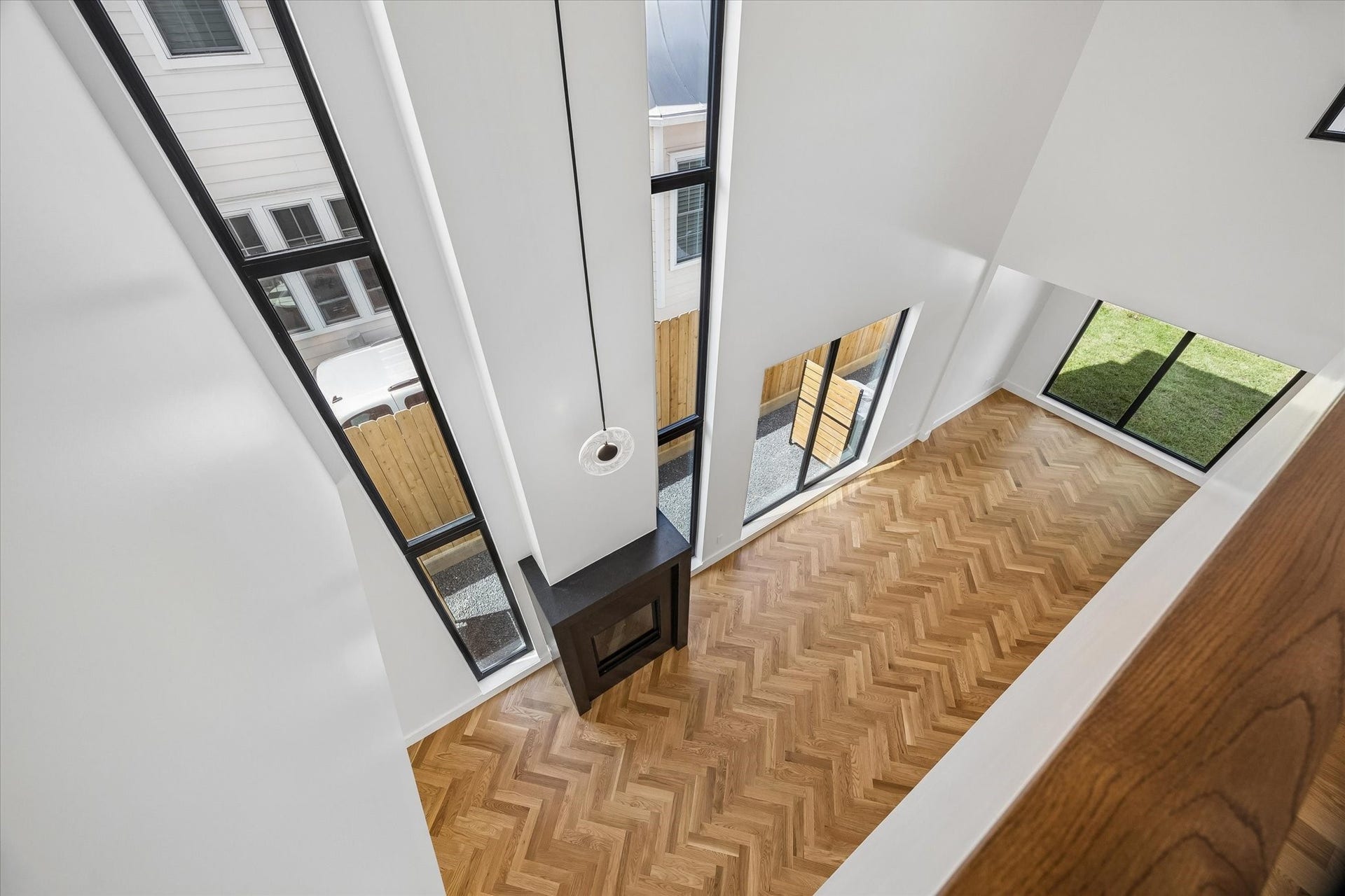 Stunning open-concept space with soaring ceilings, elegant herringbone wood floors, and abundant natural light from floor-to-ceiling windows.