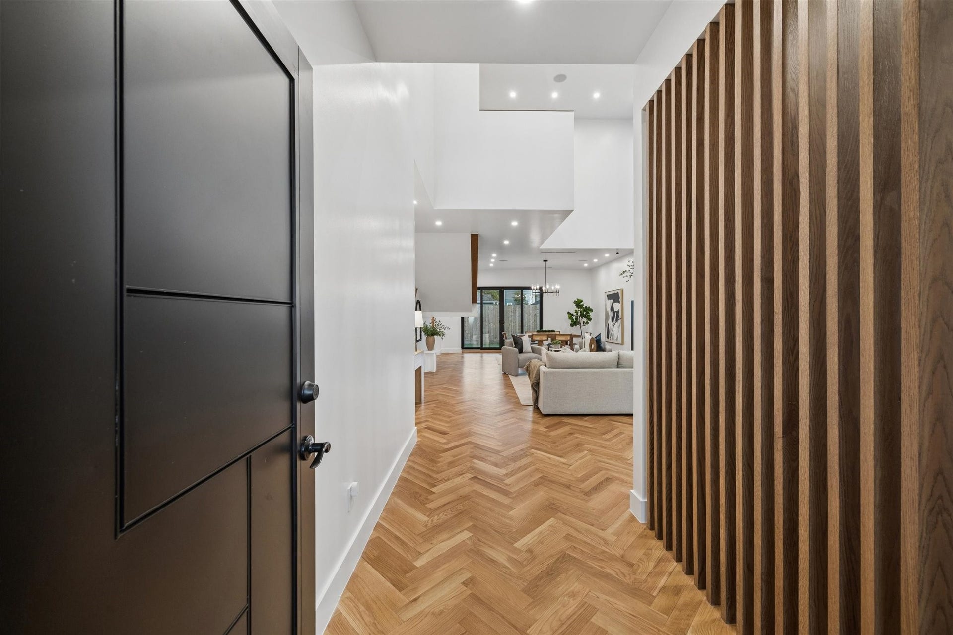 Stunning open-concept living area with high ceilings, herringbone white oak hard wood floors, and large windows that flood the space with natural light.