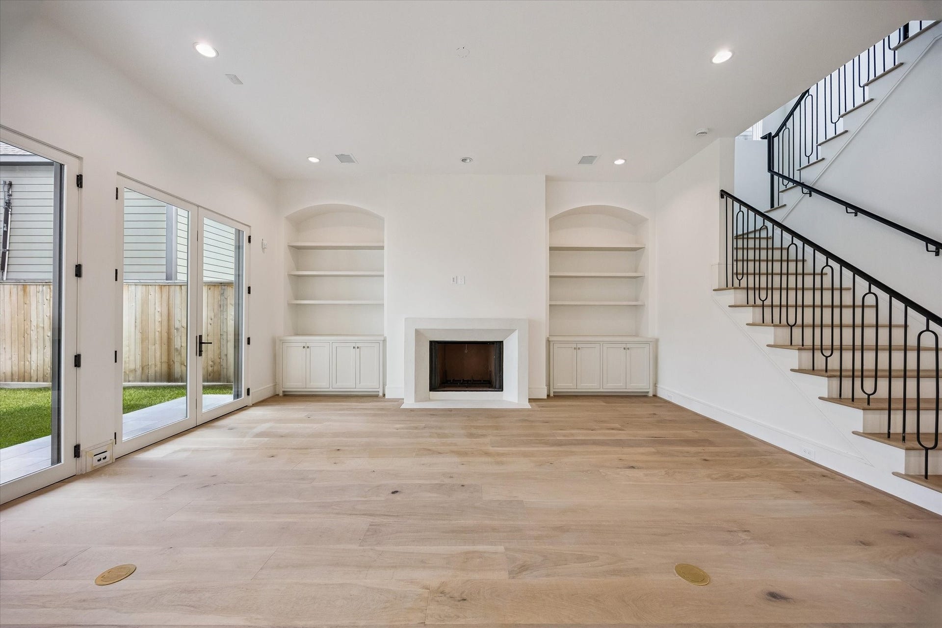 Family room with custom plastered fireplace mantle and wrought iron handrail / balusters on staircase.