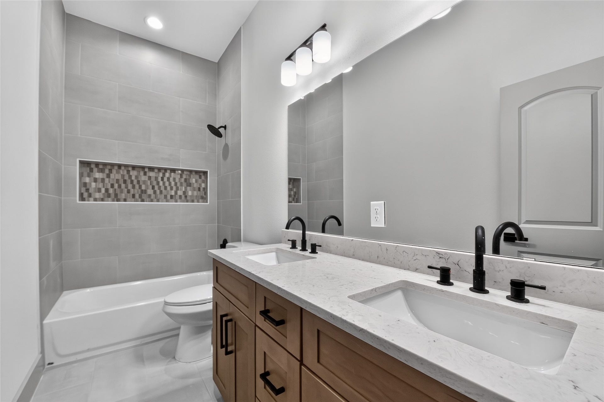 Double the vanity, double the storage. This sleek secondary bathroom offers two sinks, an expansive full-width mirror, and a tub/shower combo built for daily utility.