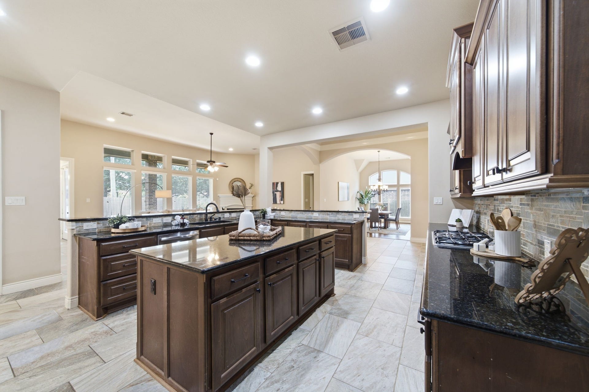 4603 Piper Shadow Lane, Katy, TX 77494 Spacious kitchen with rich wooden cabinetry, modern granite countertops, and an expansive island. The open-concept design flows seamlessly into the dining area, enhanced by ample natural light and elegant tile flooring.