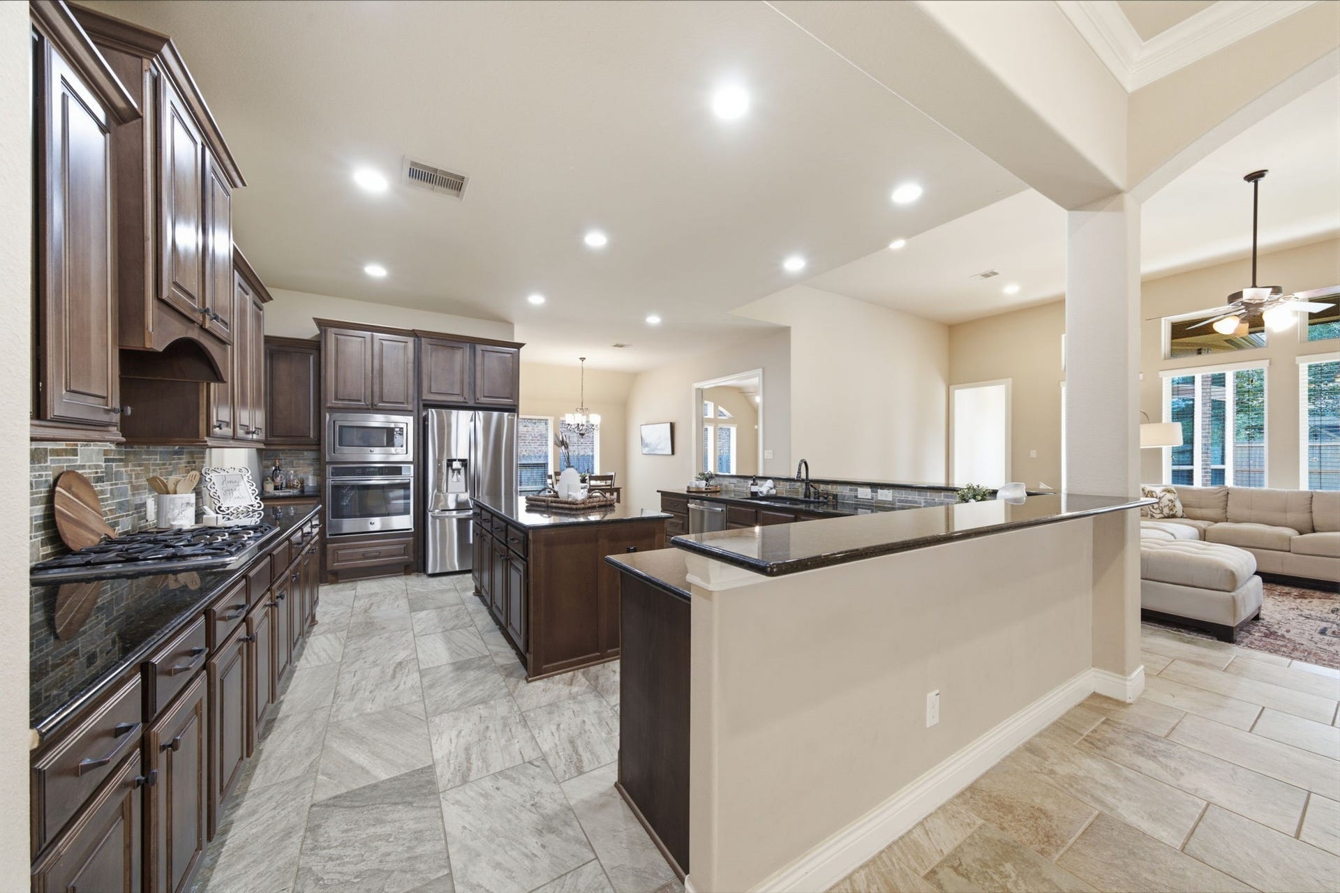 4603 Piper Shadow Lane, Katy, TX 77494 Spacious kitchen with elegant dark wood cabinetry, modern stainless steel appliances, and a sleek granite countertop that seamlessly flows into the open living area.