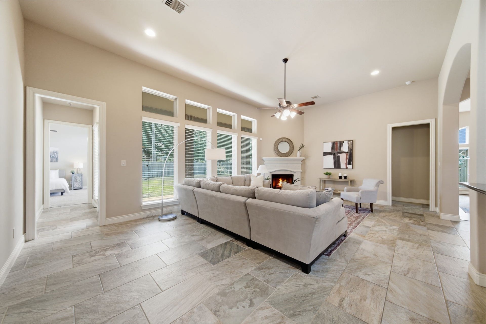 4603 Piper Shadow Lane, Katy, TX 77494 Spacious living room with elegant tile flooring, a cozy fireplace, and abundant natural light from large windows, seamlessly connected to a welcoming hallway and adjacent rooms.