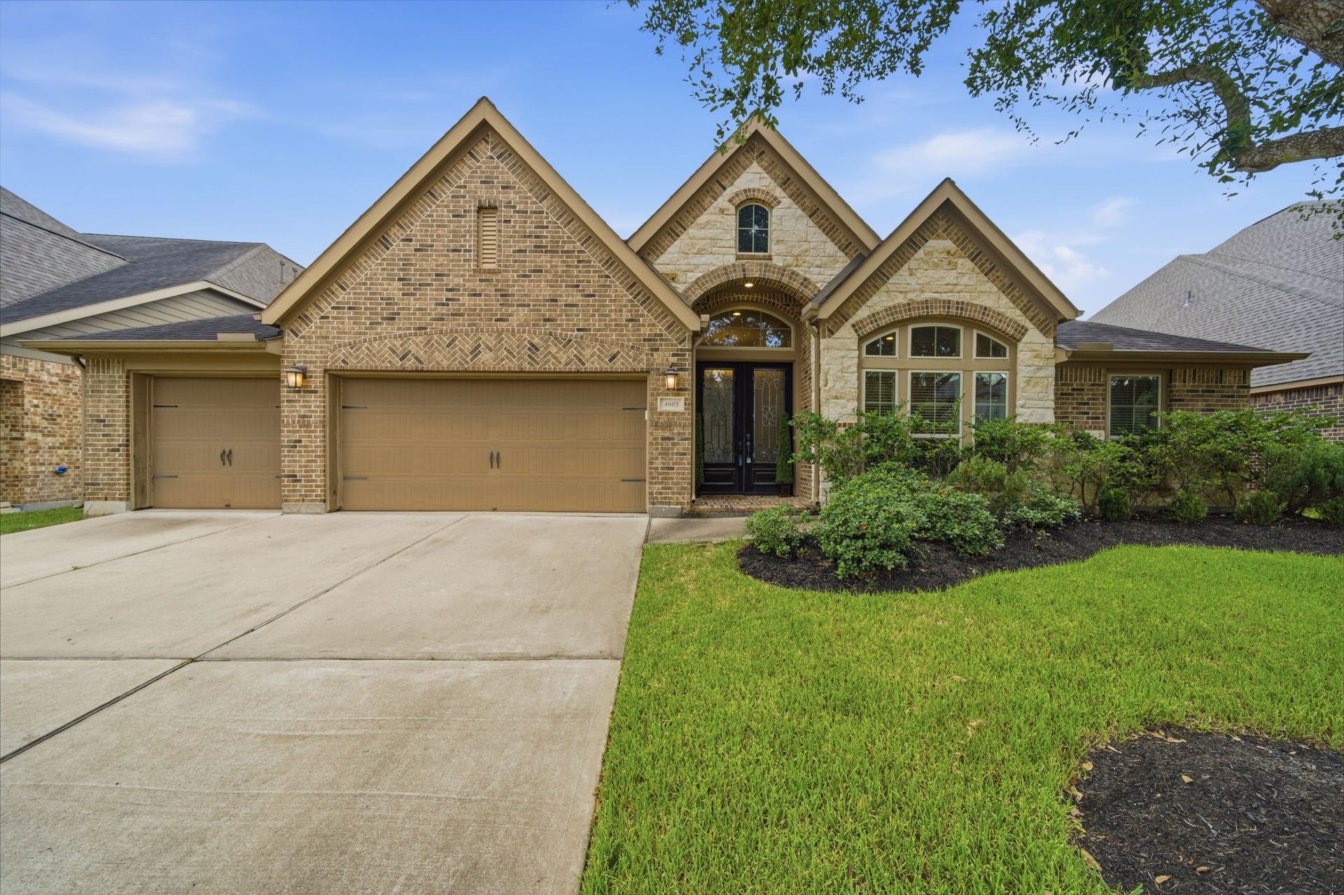 4603 Piper Shadow Lane, Katy, TX 77494 Charming brick home with a three-car garage and inviting arched entryway, surrounded by lush landscaping and a well-maintained lawn.