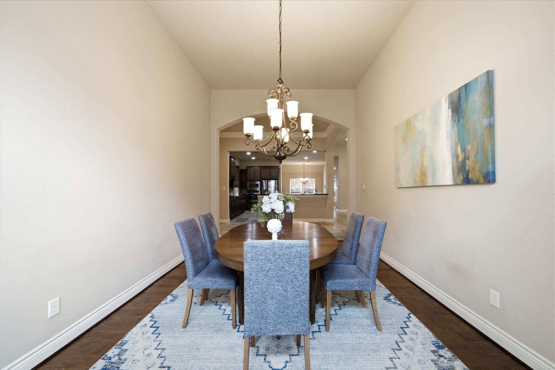 4603 Piper Shadow Lane, Katy, TX 77494 Elegant dining room with a high ceiling, featuring a stylish chandelier, a wooden table, and modern chairs. The space leads into an open kitchen area.