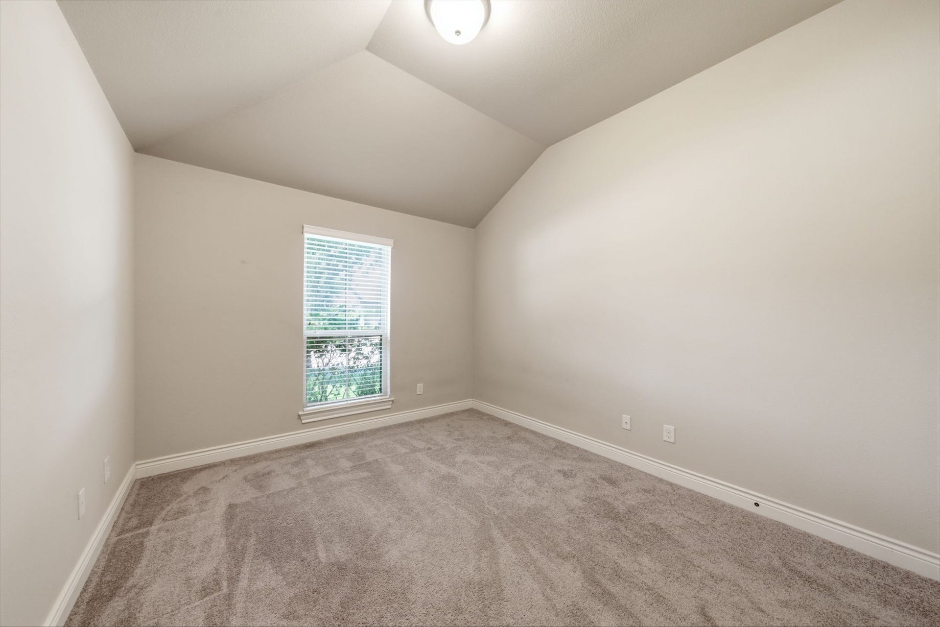 4603 Piper Shadow Lane, Katy, TX 77494 Cozy bedroom with vaulted ceiling, soft carpeting, and natural light streaming through a large window.