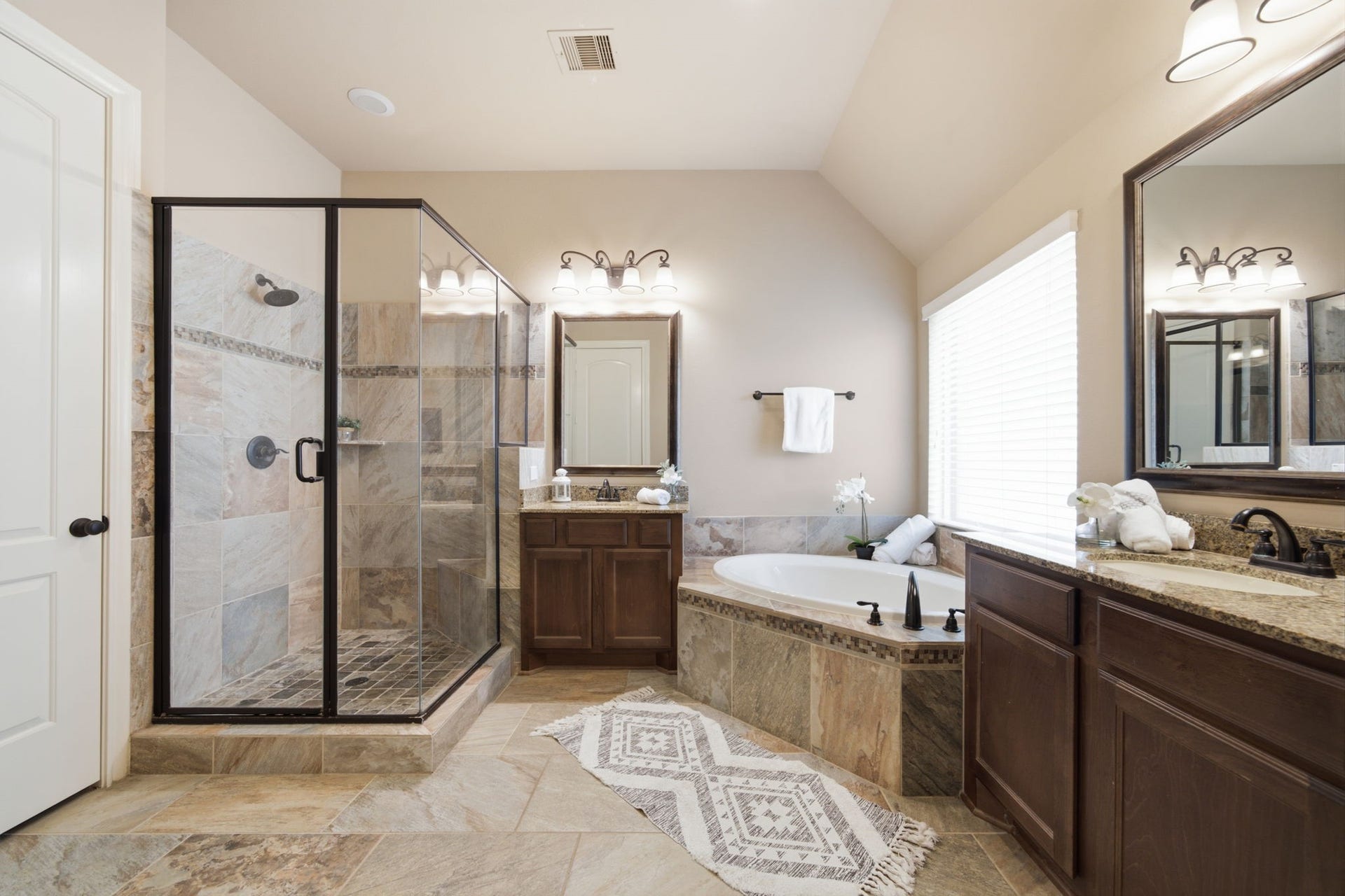4603 Piper Shadow Lane, Katy, TX 77494 Elegant bathroom featuring a spacious walk-in shower with glass doors, a luxurious soaking tub, dual sinks with granite countertops, and rich wood cabinetry.