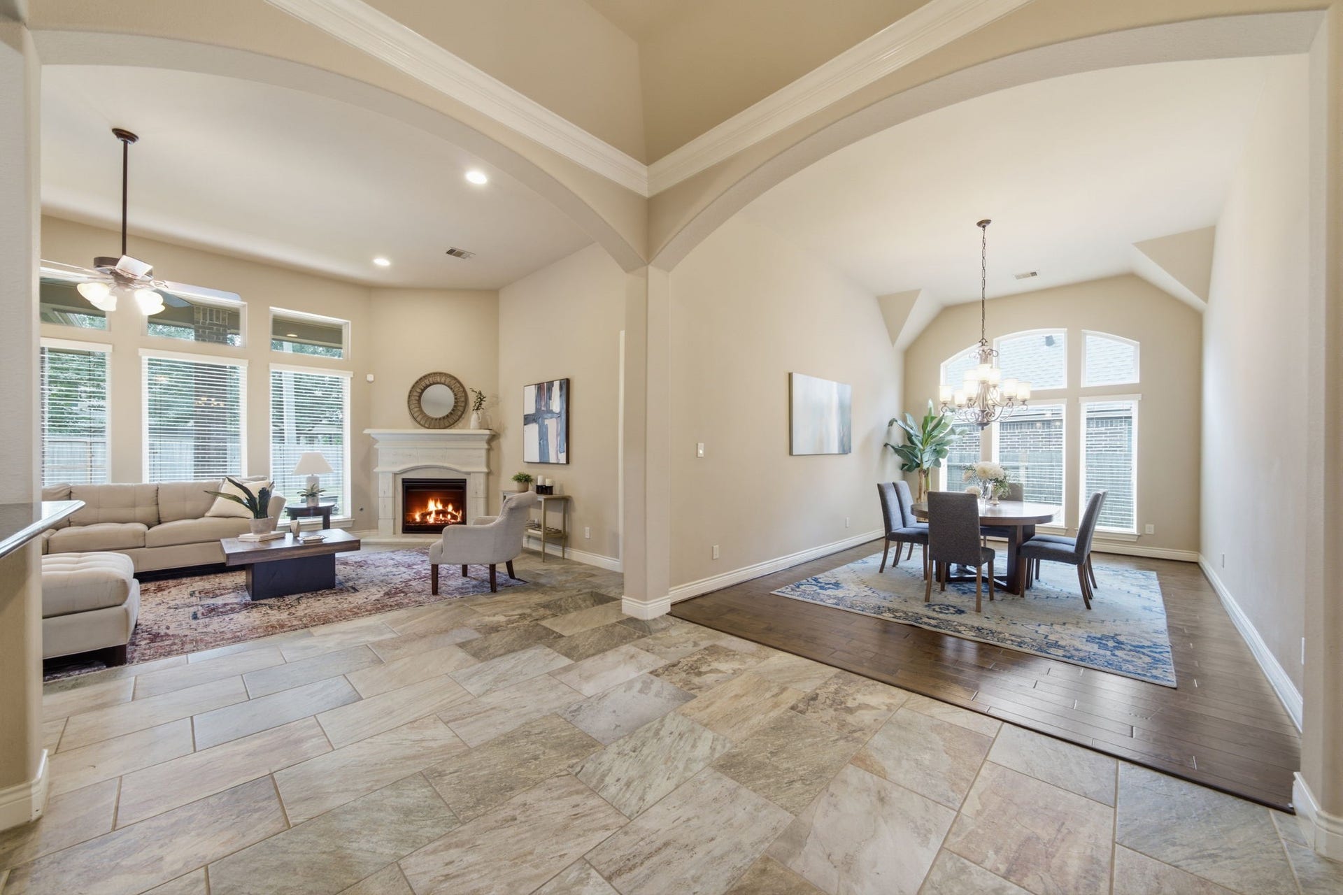4603 Piper Shadow Lane, Katy, TX 77494 Spacious open-concept living area with elegant archways, featuring a cozy fireplace and abundant natural light from large windows, seamlessly flowing into a formal dining space with a stylish chandelier.