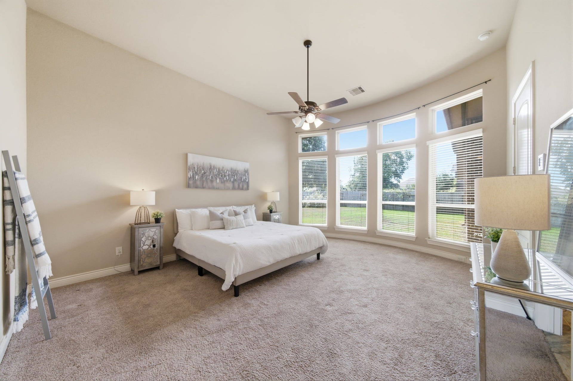 4603 Piper Shadow Lane, Katy, TX 77494 Spacious primary bedroom with abundant natural light from large arched windows, featuring a cozy carpeted floor and elegant ceiling fan.