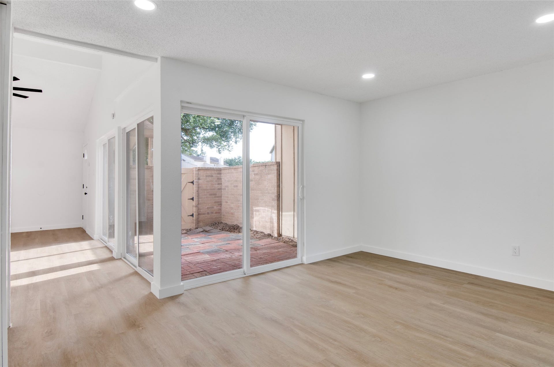2916 Windchase Blvd, Houston, TX 77082 Bright and airy living space featuring sleek wood flooring, recessed lighting, and large sliding glass doors that open to a private patio.