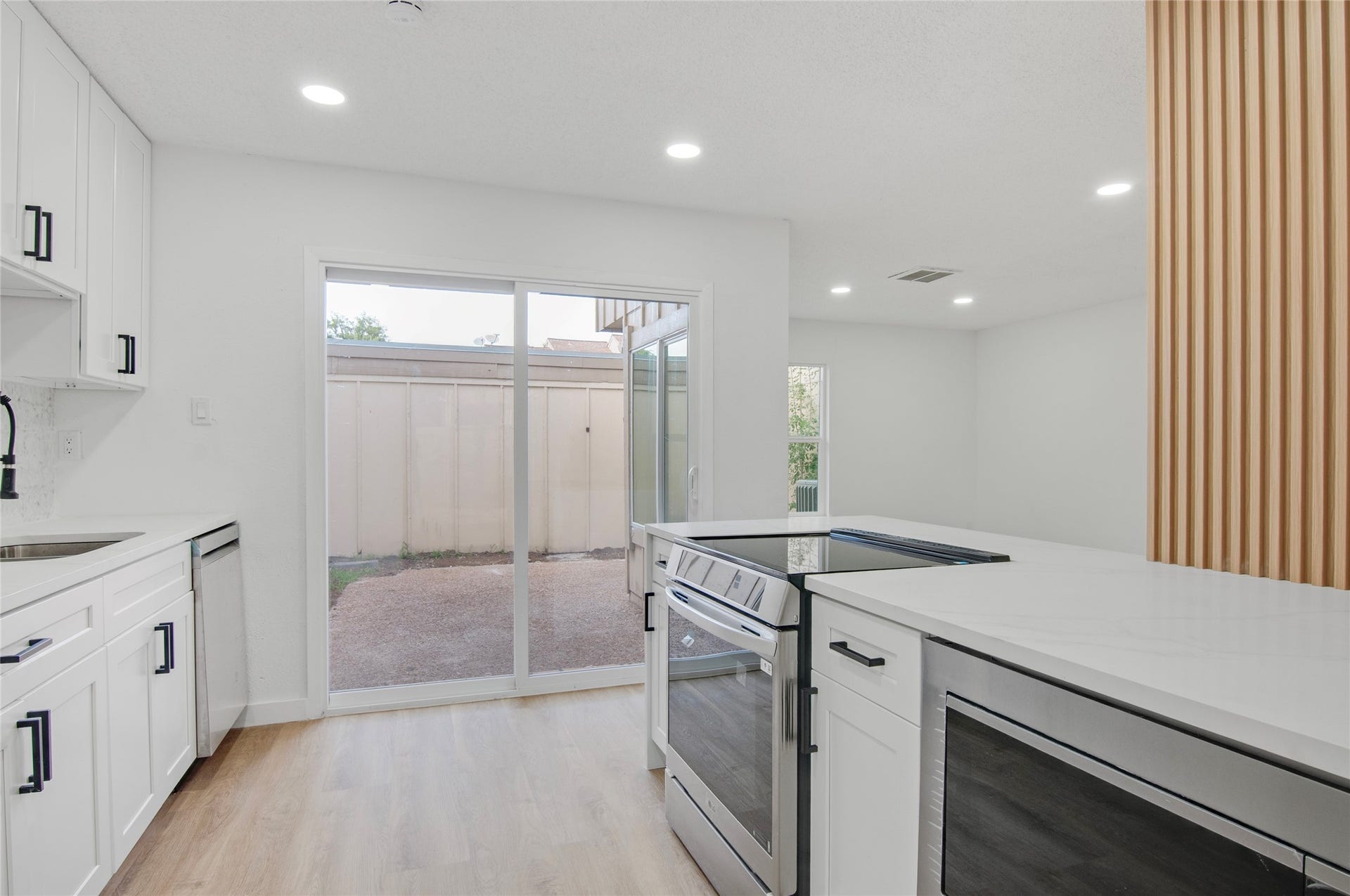 2916 Windchase Blvd, Houston, TX 77082 Bright and modern kitchen with sleek appliances, white cabinetry, and a large sliding glass door leading to a private outdoor space.
