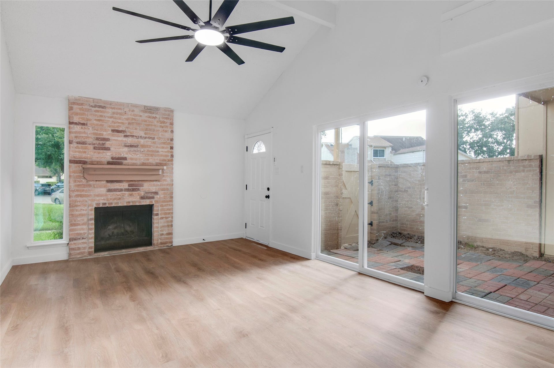2916 Windchase Blvd, Houston, TX 77082 Bright living space featuring a vaulted ceiling, cozy brick fireplace, and new large sliding glass doors leading to a private patio.