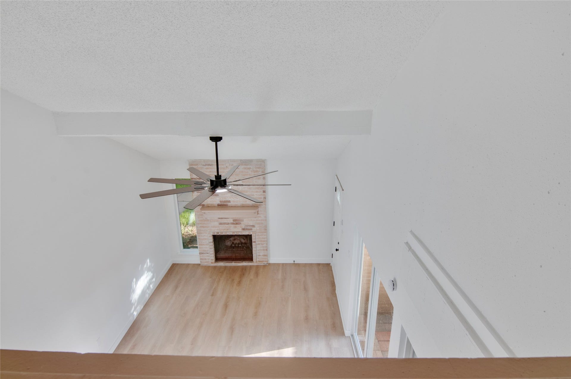 2916 Windchase Blvd, Houston, TX 77082 Spacious living area with a charming brick fireplace, sleek ceiling fan, and abundant natural light from large windows.