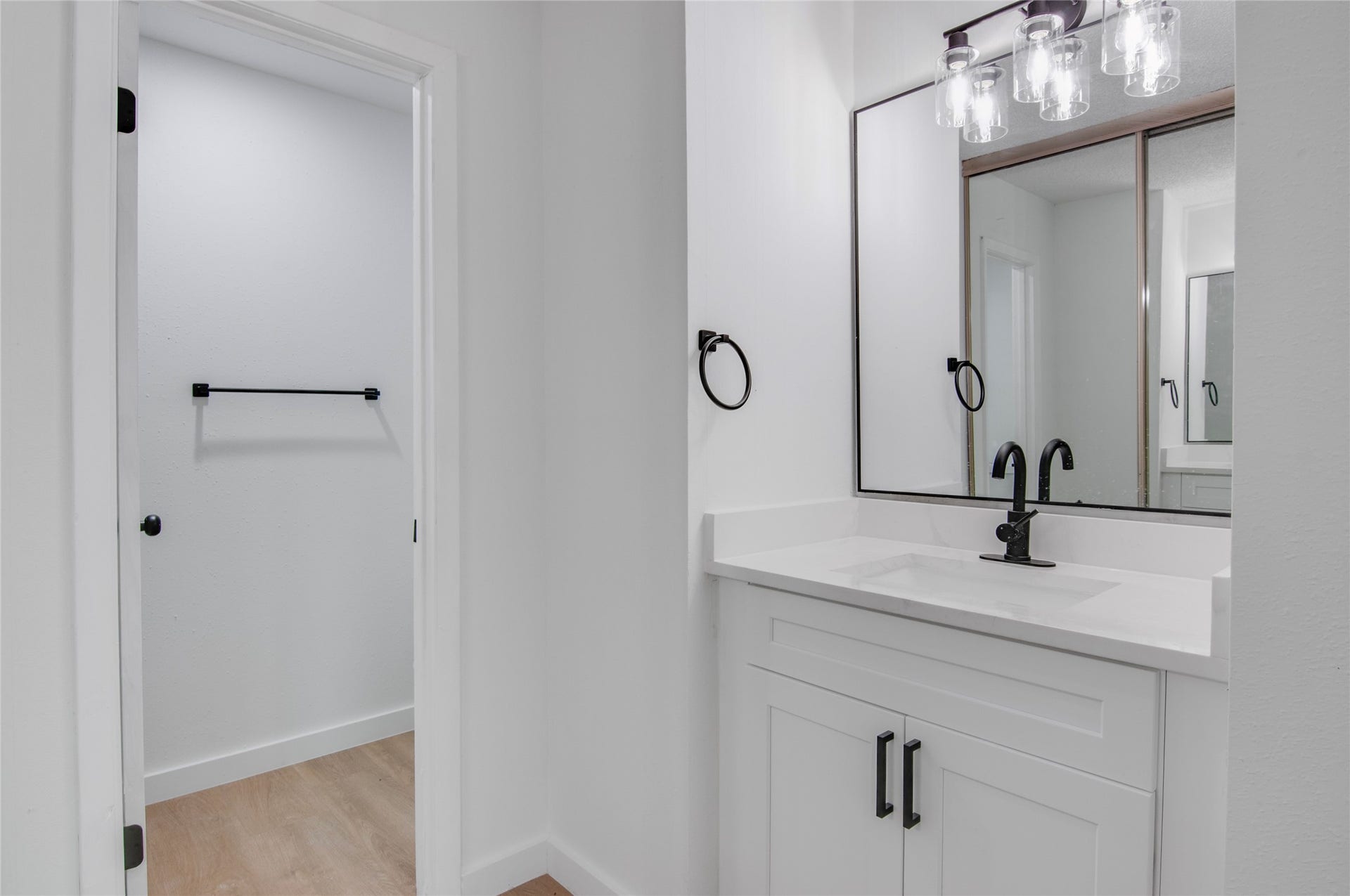 2916 Windchase Blvd, Houston, TX 77082 Sleek and modern bathroom features a stylish vanity with a black faucet, large framed mirror, and ample lighting, leading to a spacious walk-in closet.