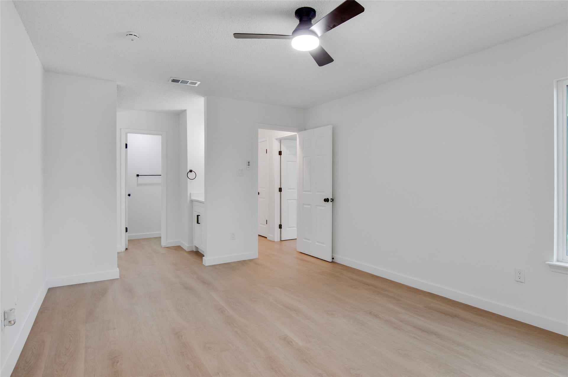 2916 Windchase Blvd, Houston, TX 77082 Spacious bedroom with sleek laminate flooring, modern ceiling fan, and ample natural light, featuring an en-suite bathroom and walk-in closet.