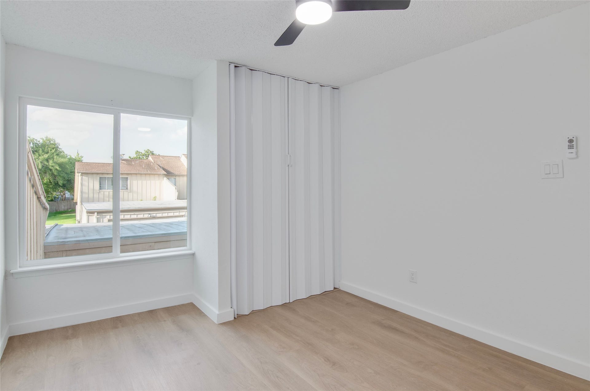 2916 Windchase Blvd, Houston, TX 77082 Bright and airy room with large window, sleek ceiling fan, and modern laminate flooring, perfect for a cozy living space.